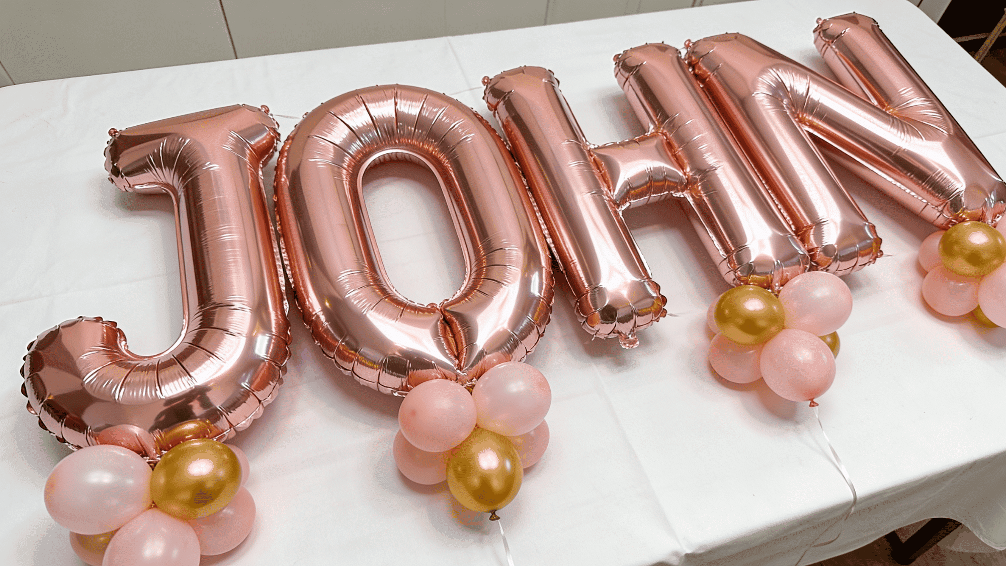 rose gold foil letter balloons spelling a name on a white party table with blush and gold accent balloons (1)