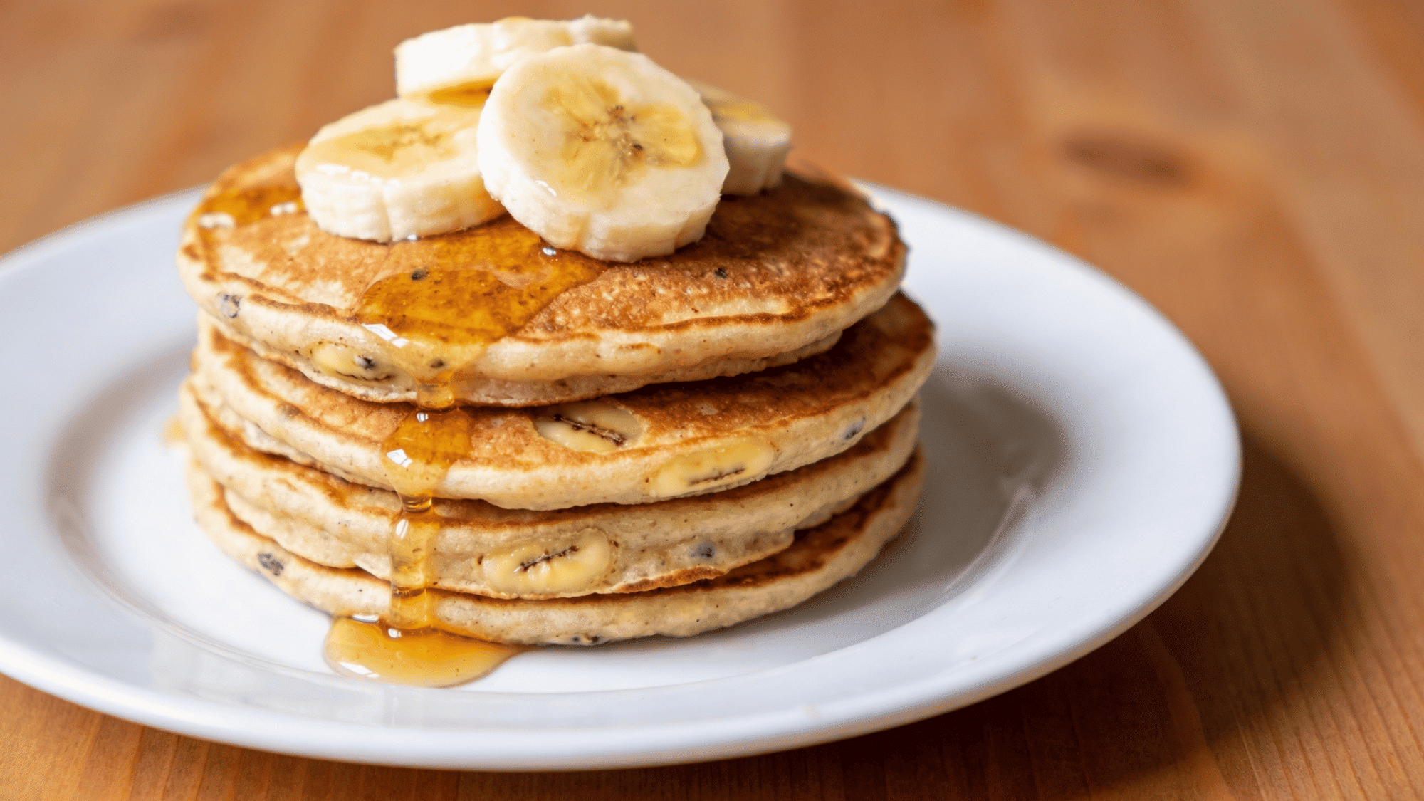 stack of golden banana oat pancakes with banana slices and honey drizzle, healthy breakfast meal idea for kids