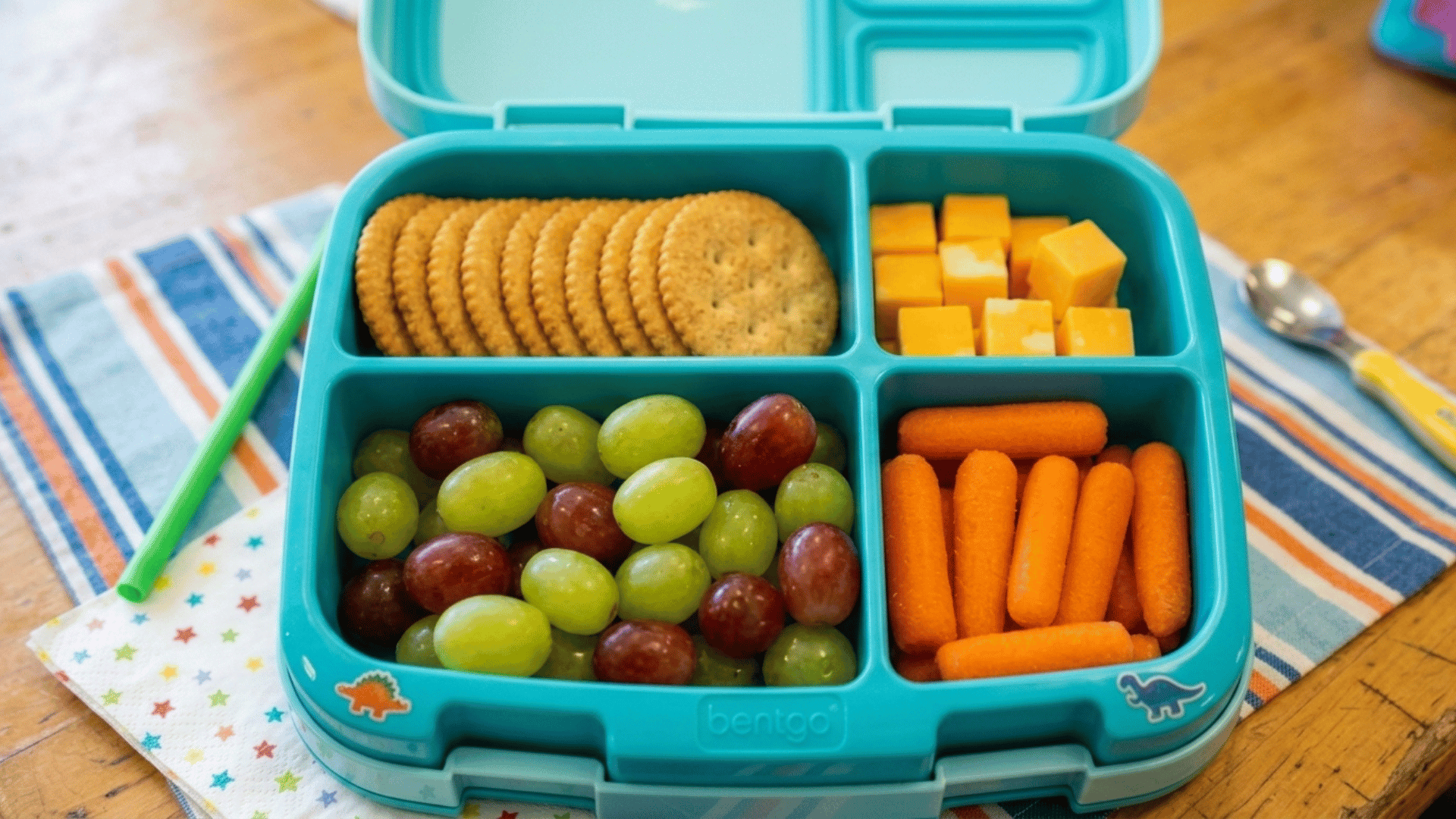 bento box with crackers, cheese cubes, grapes, and carrots