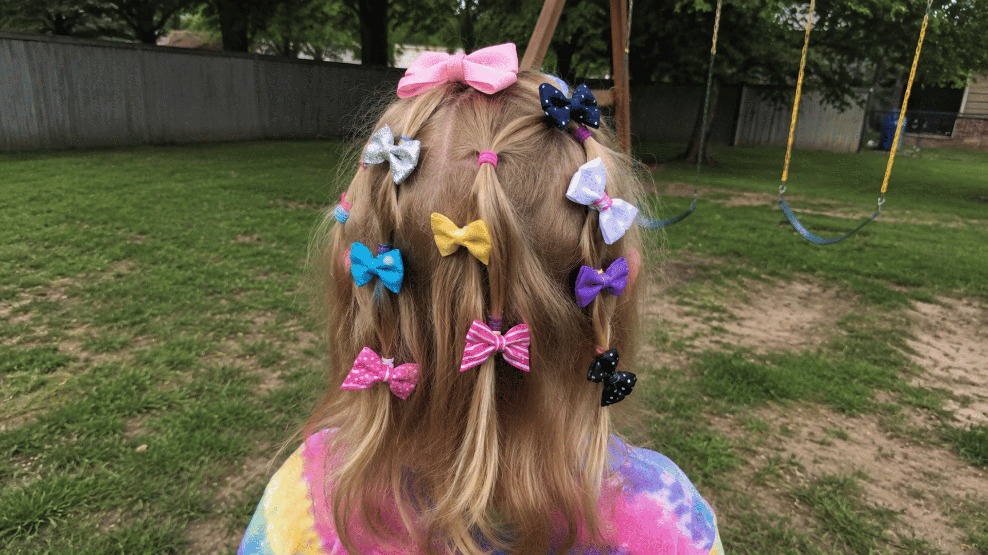 blonde hair sectioned with mismatched fabric bows scattered playfully at playground