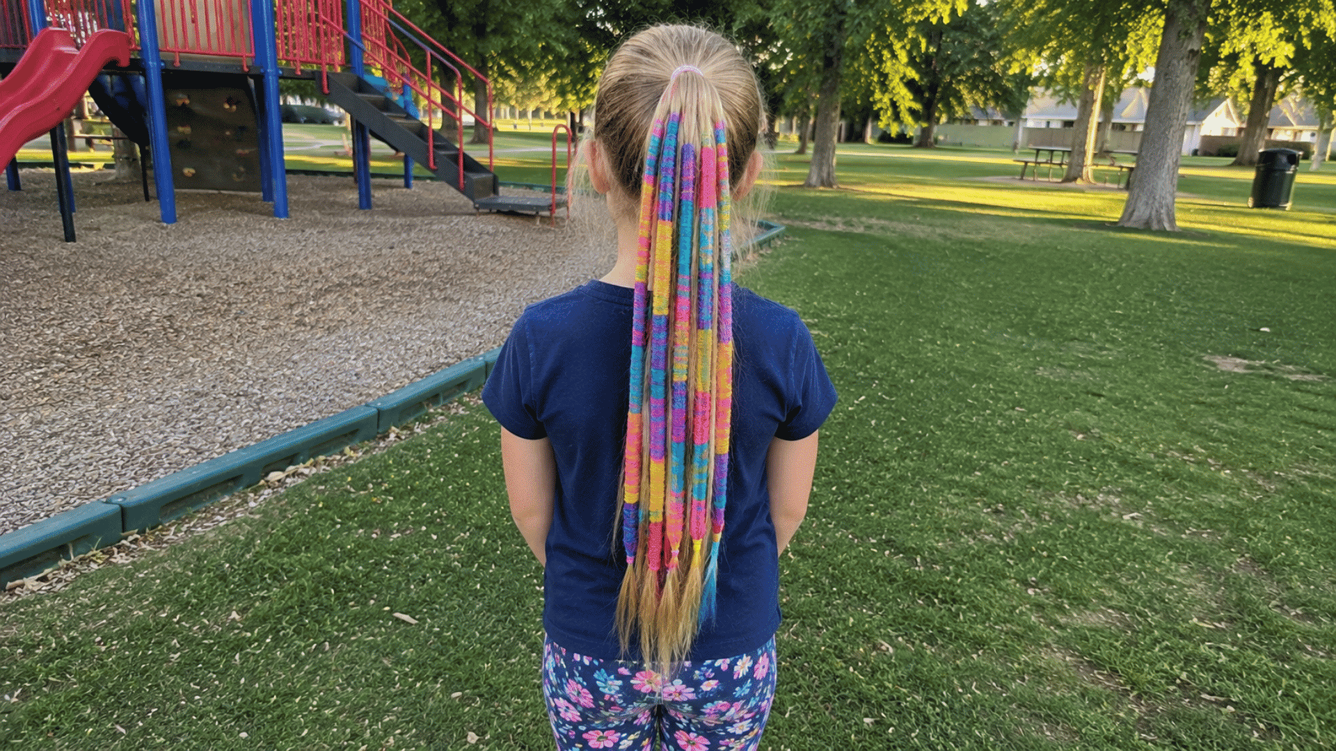 blonde ponytail wrapped in colorful striped yarn at playground park