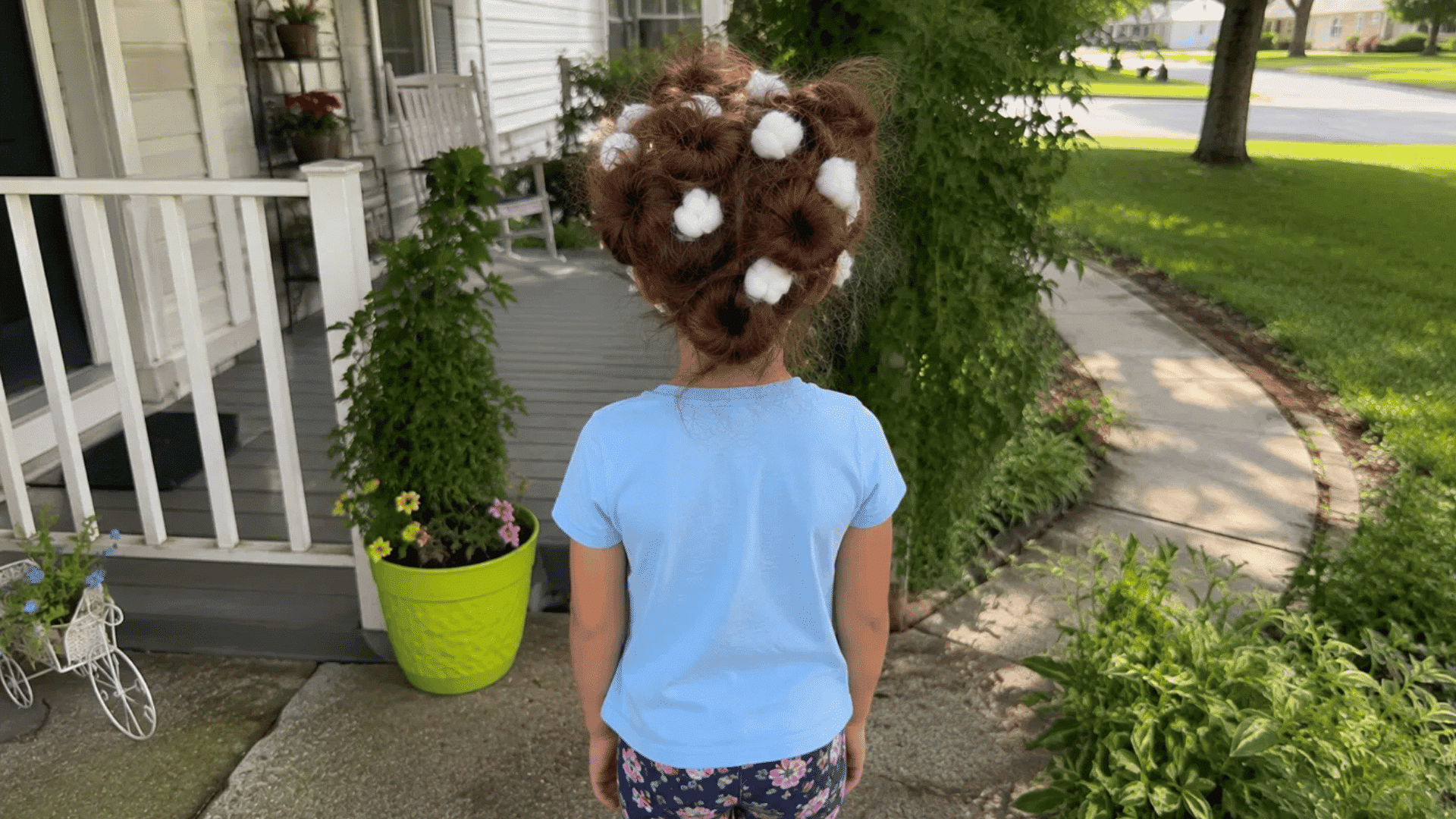 brown hair with fluffy cotton balls tucked into puffs on front porch