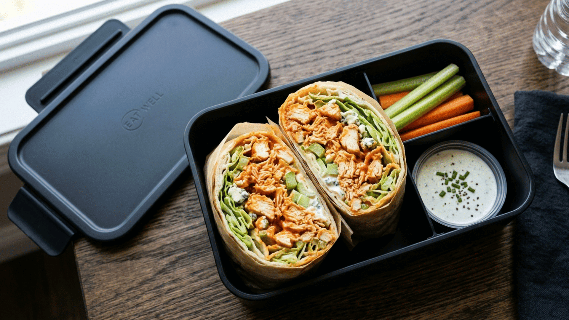 buffalo chicken wrap sliced in half packed in a black teen lunchbox