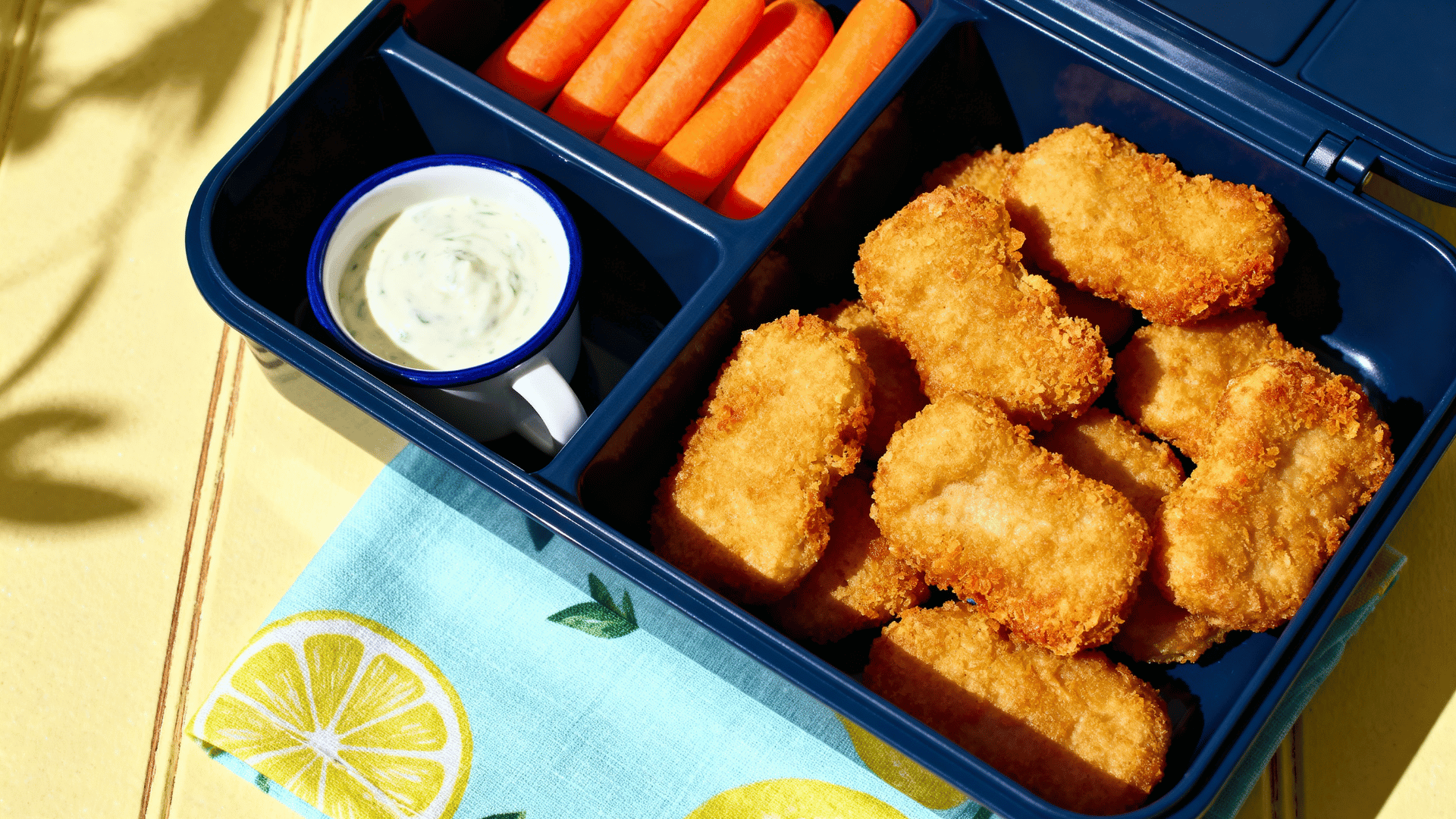 chicken nuggets and carrots arranged in a navy blue bento lunchbox