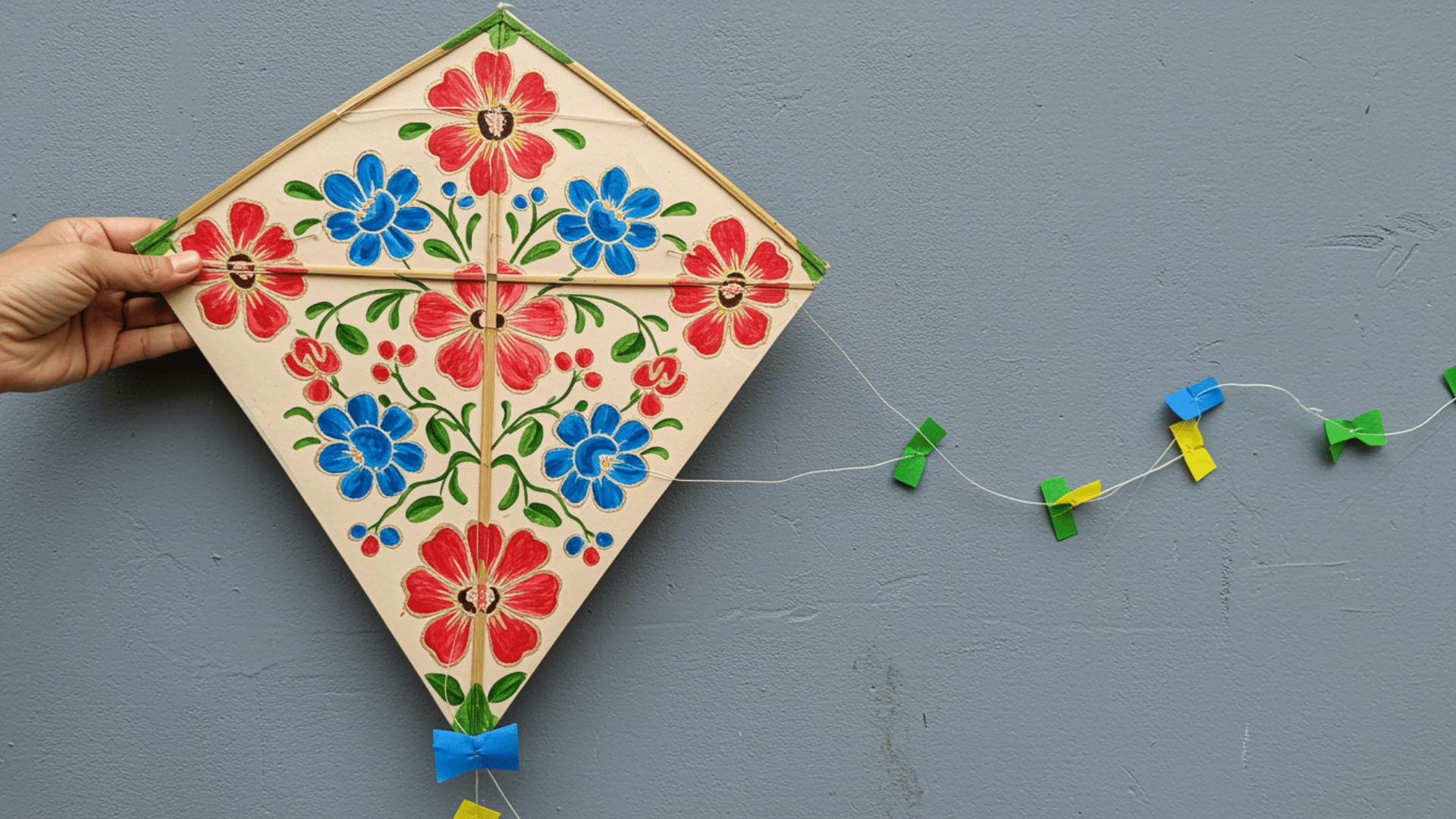 colorful diamond shaped, floral printed paper kite with a long ribbon tail and string attached