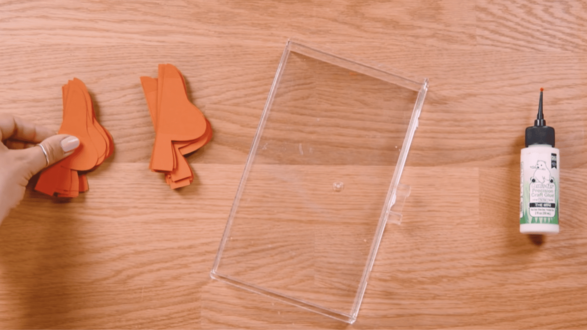 crafting setup with cardstock pieces, glue, scissors, and a box placed nearby for alignment support