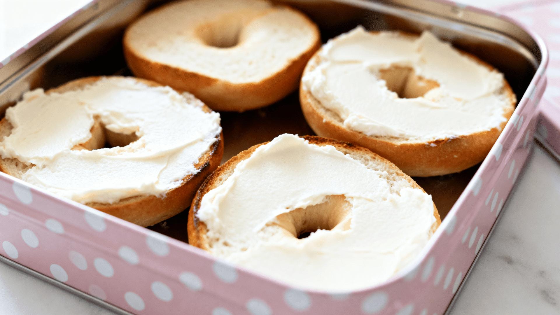 mini bagels with cream cheese in a pink and white polka-dot lunch tin