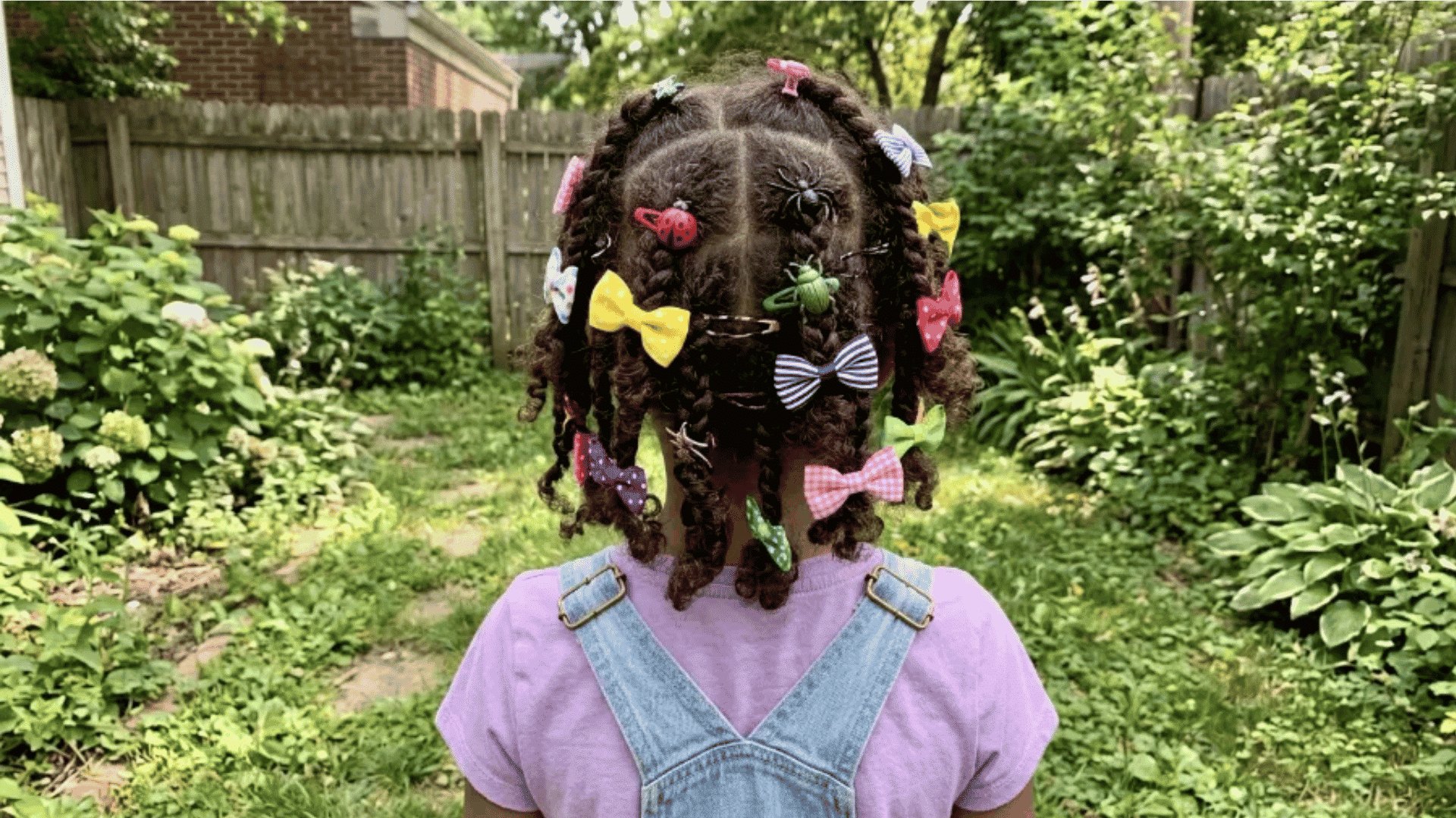 curly hair with plastic bugs and mismatched bows in garden path