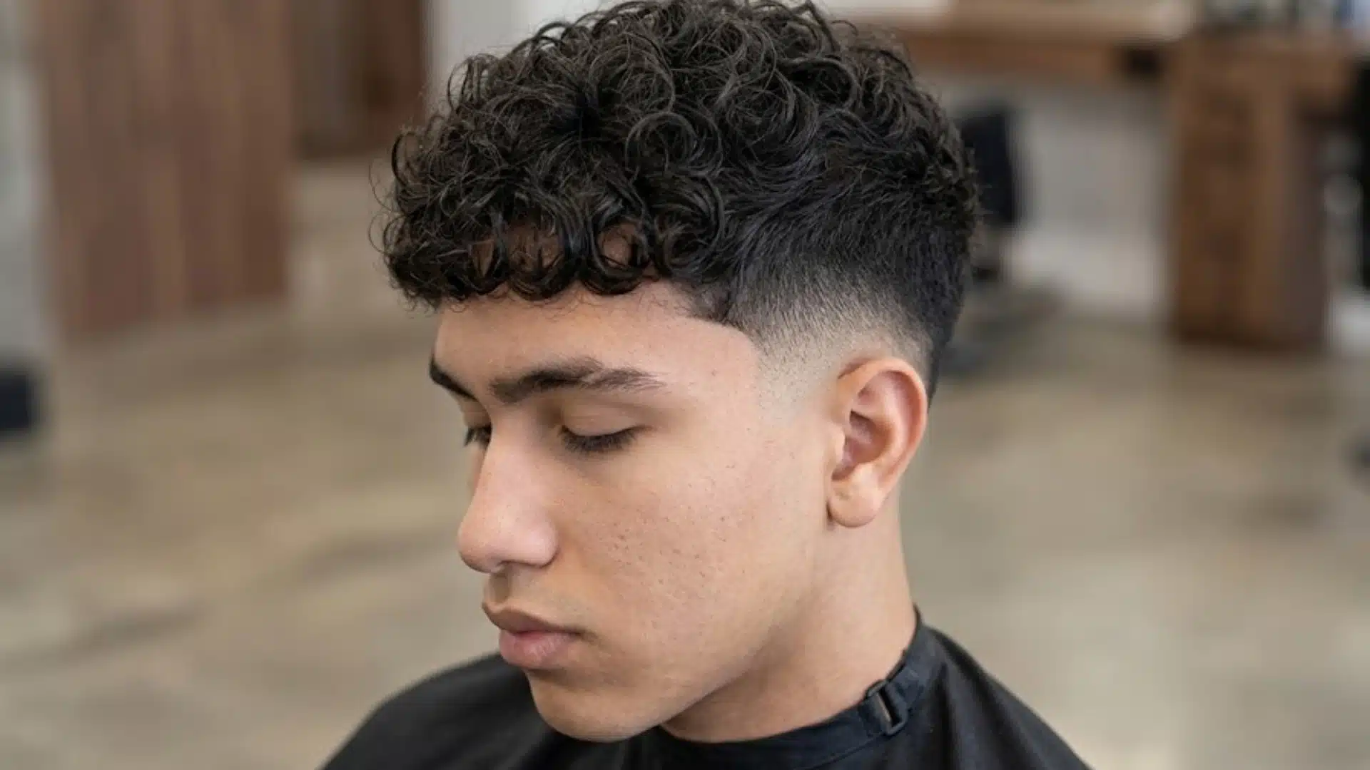 curly textured crop with a low fade haircut on a teenage boy featuring defined curls and clean tapered sides