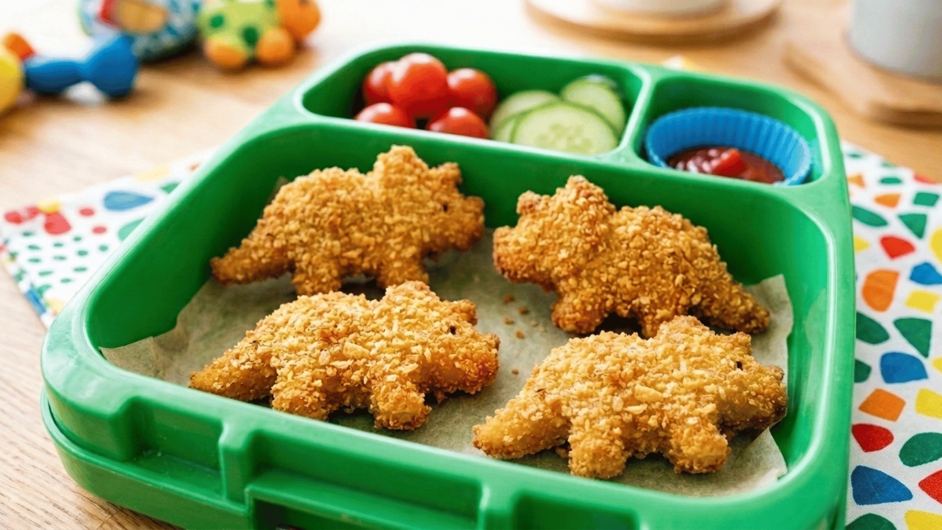 dinosaur-shaped chicken bites packed in a green kids lunchbox