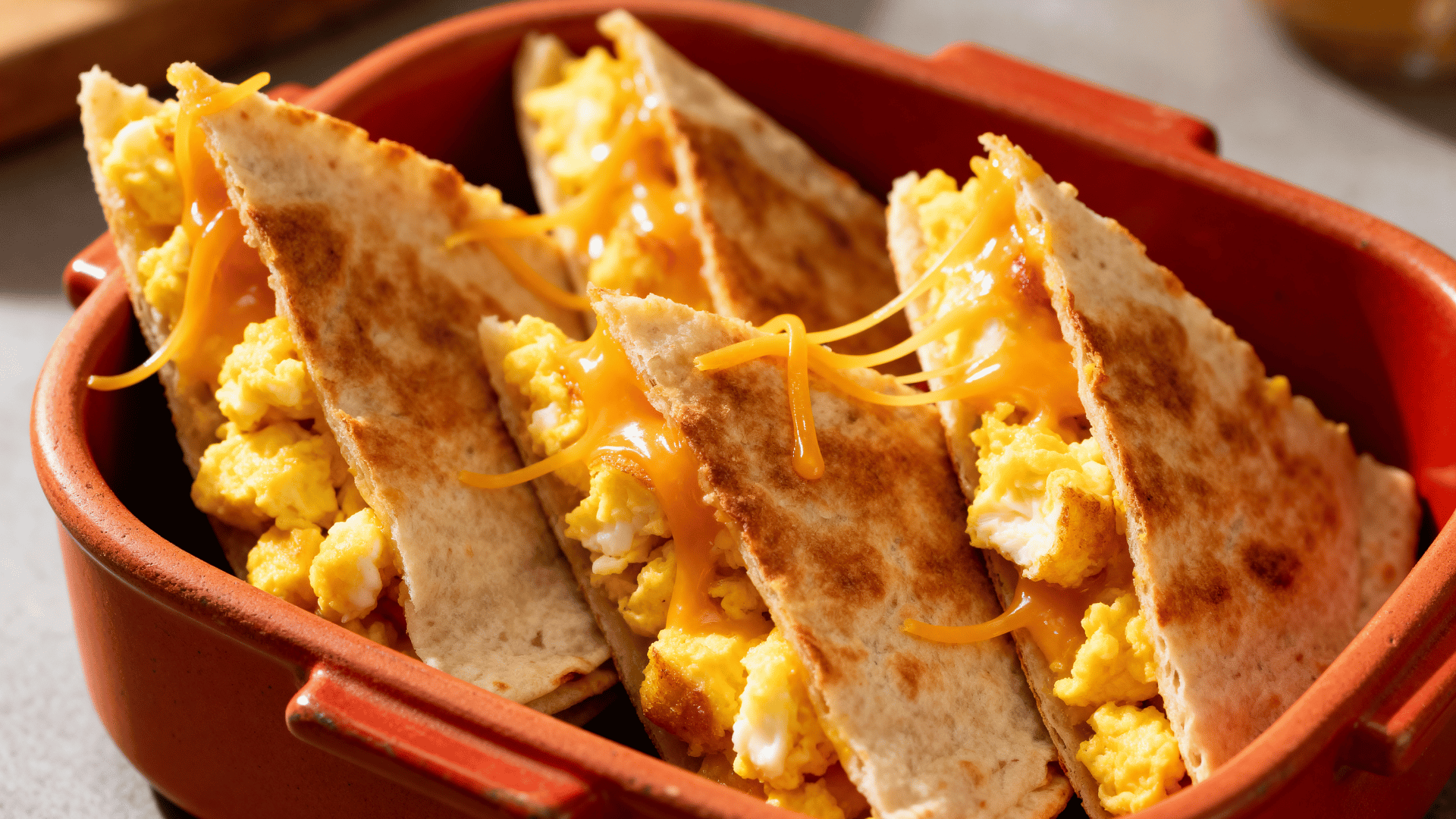 breakfast burrito wedges in a warm terracotta-red ceramic lunchbox