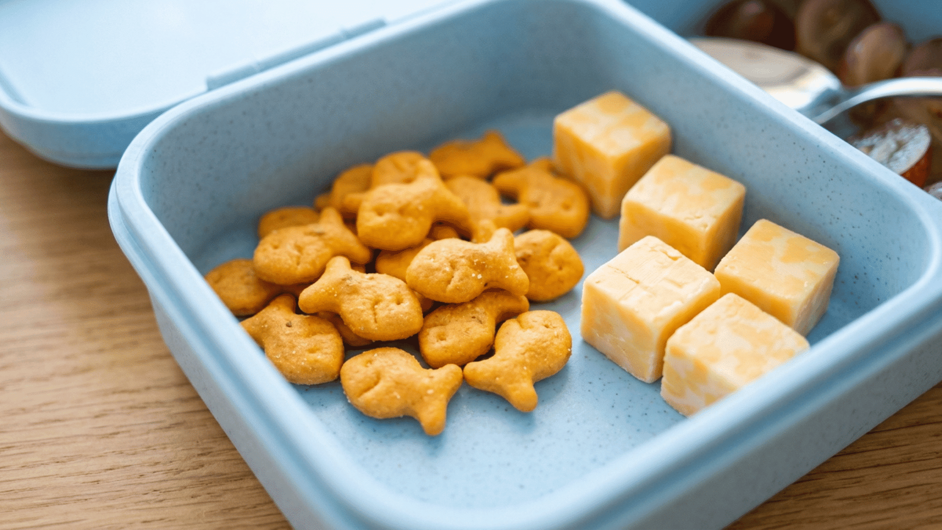 fish-shaped crackers and cheese cubes packed in a blue plastic lunchbox