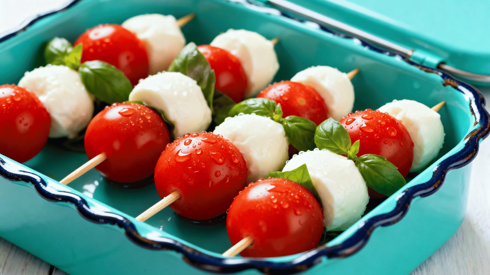 mozzarella, tomato, and basil skewers in a turquoise scalloped enamel lunch tin