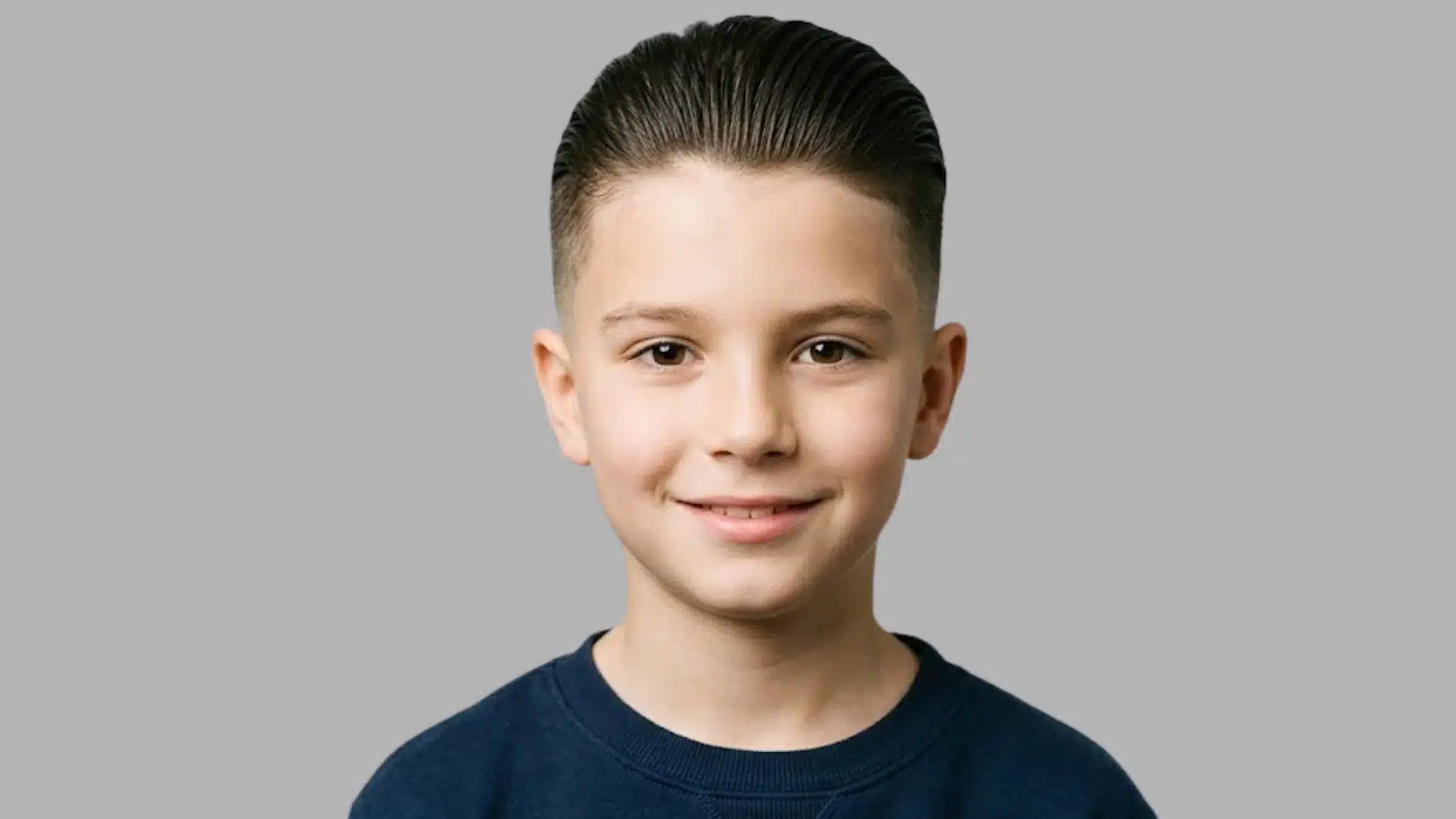 front view of a young boy with a slick back hairstyle featuring a clean fade and neatly combed glossy hair