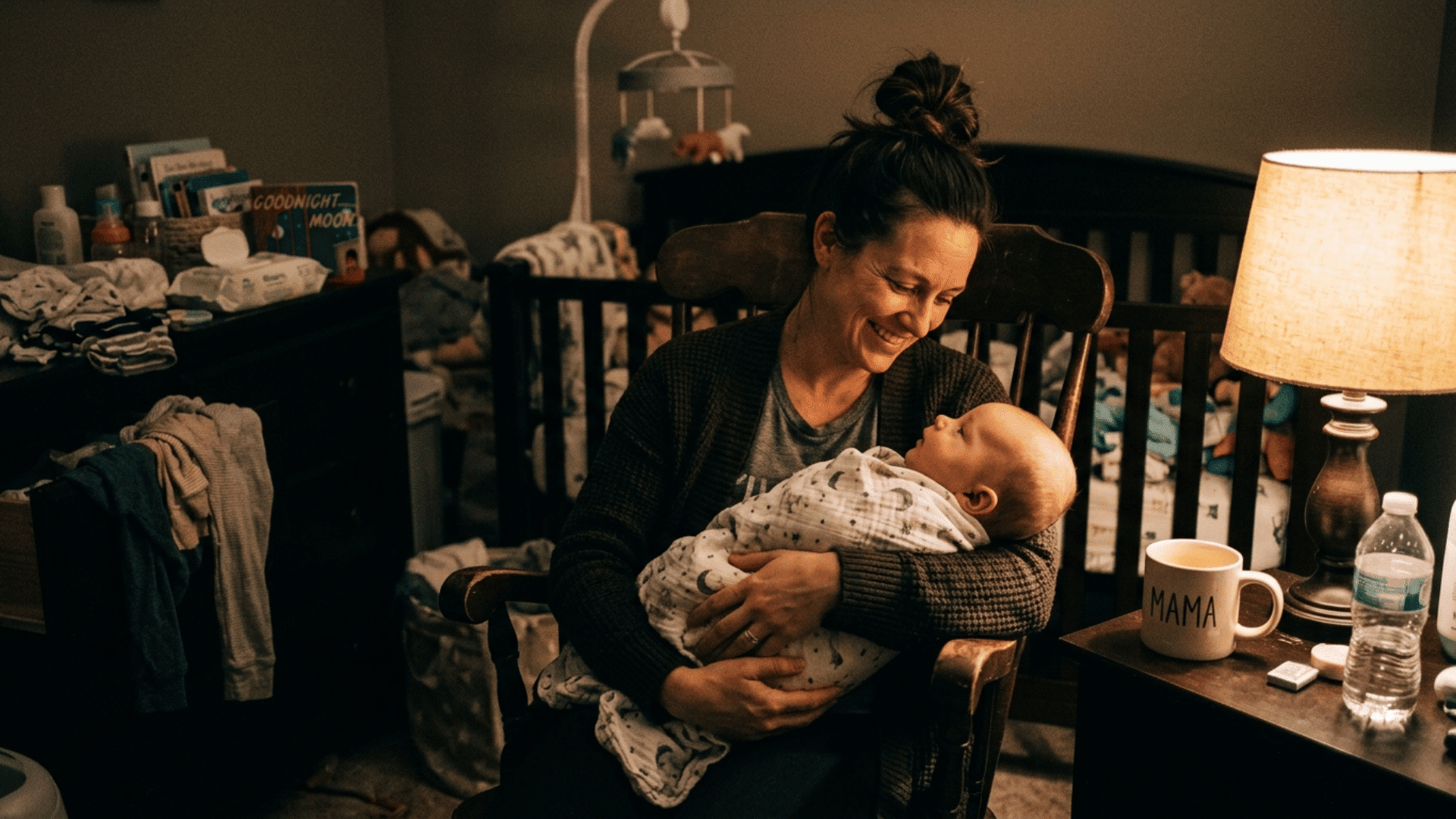 sleepy parent holding baby at night with coffee mug nearby