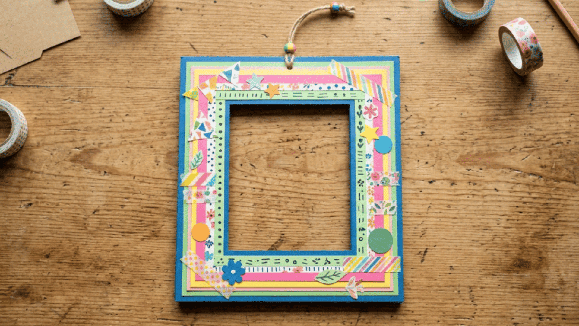 handmade paper photo frame with colorful decorations placed on a table with clean edges and empty center