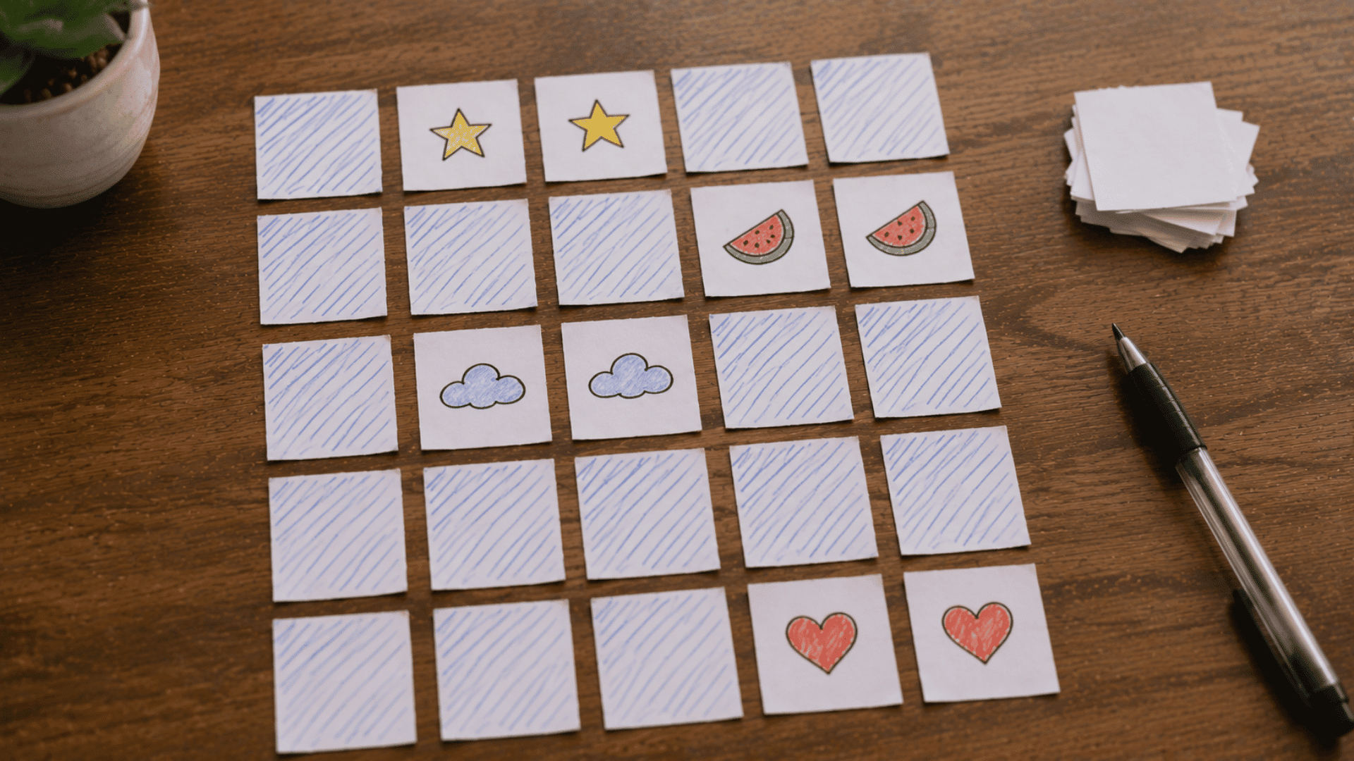 homemade memory card matching game laid out on a table with hand-drawn pairs of stars, watermelons, clouds, and hearts