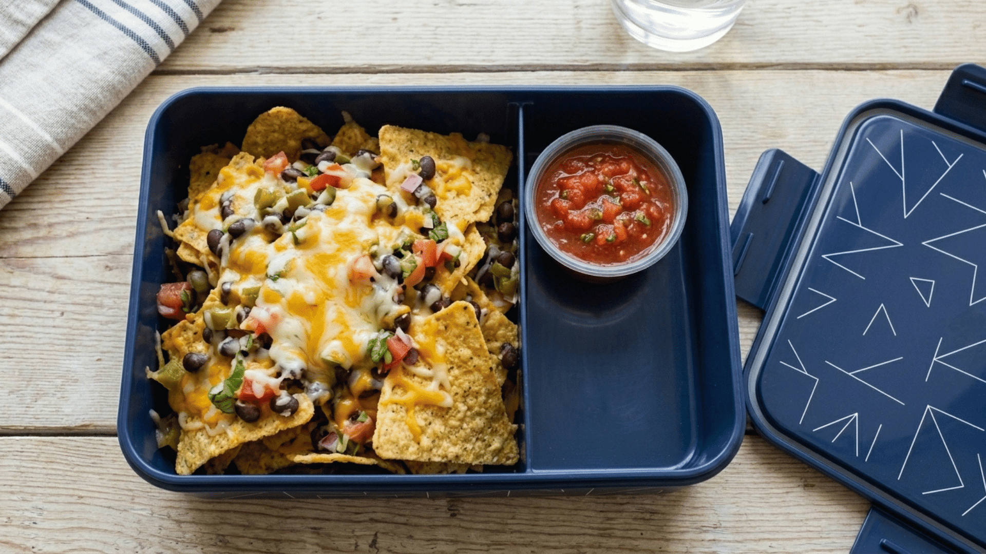 loaded nachos with cheese and salsa packed in a navy blue lunchbox
