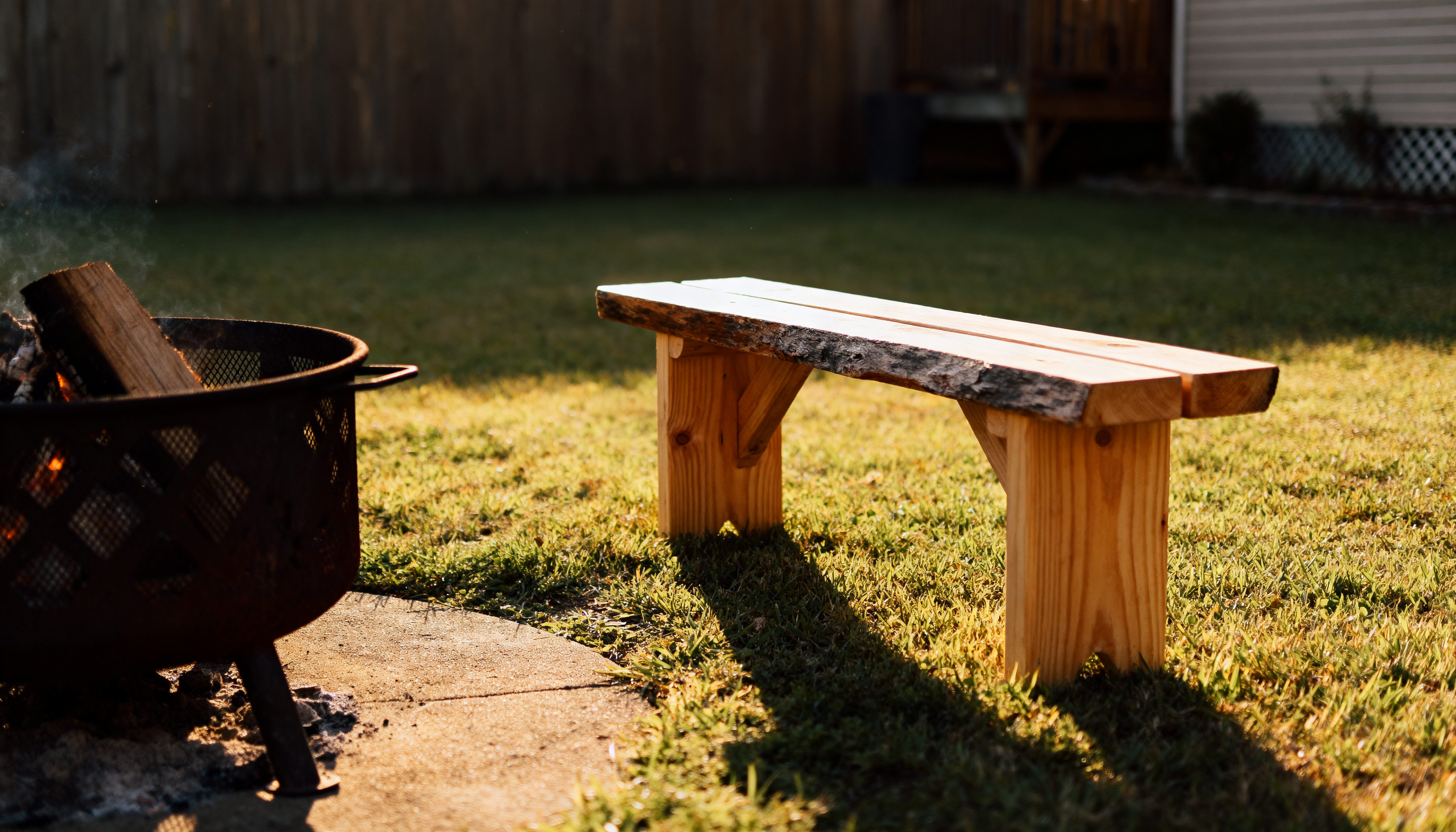 Handmade wooden bench near a backyard fire pit