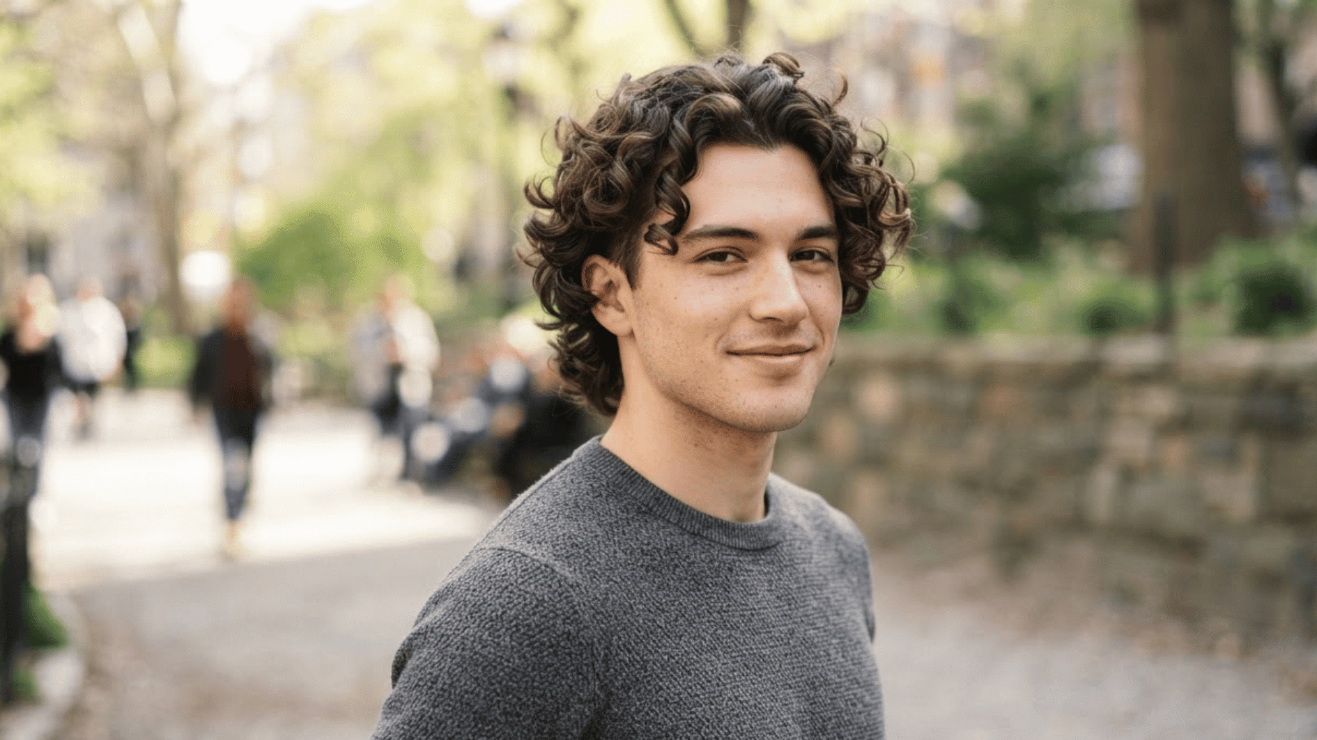 man with curly flow haircut outdoors showing natural texture and medium length layered curls