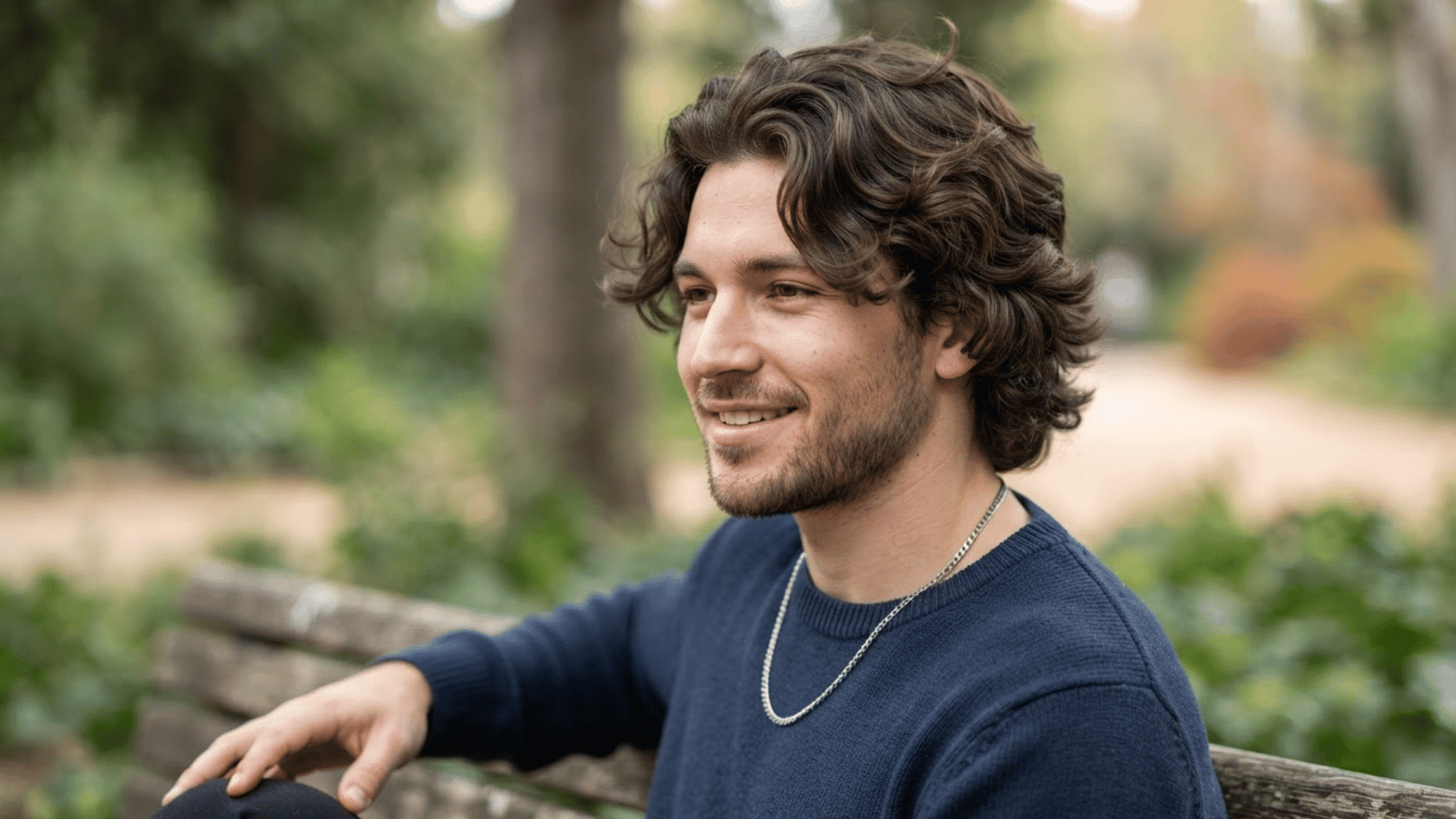 man with curly flow haircut outdoors showing textured curls and natural layered hair movement