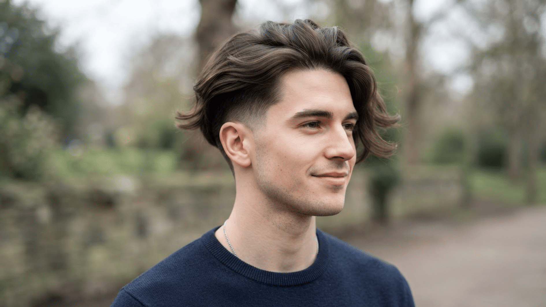 man with flow haircut and undercut outdoors showing long textured hair and faded sides