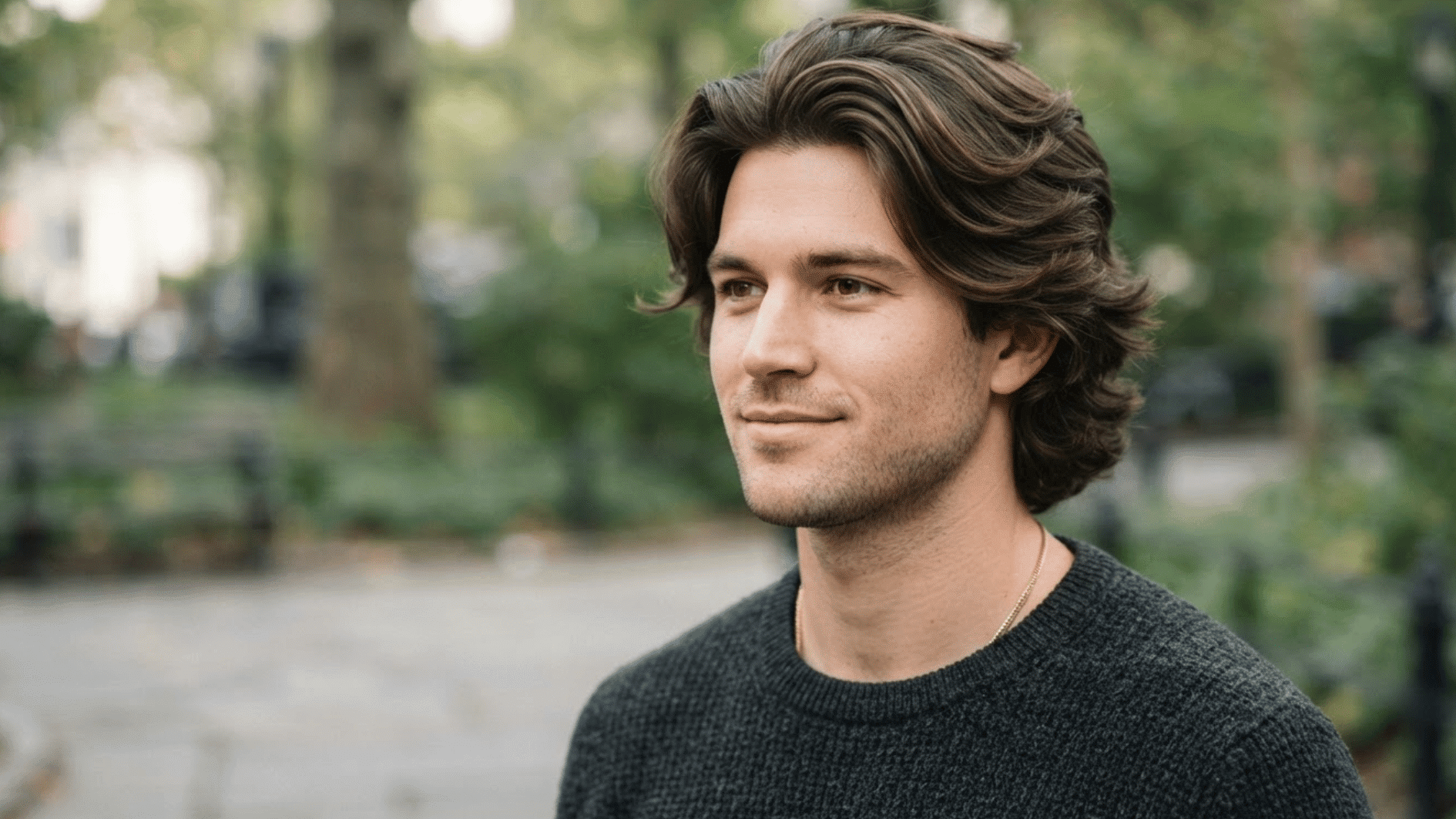 man with layered flow haircut outdoors showing thick textured hair and natural swept back style