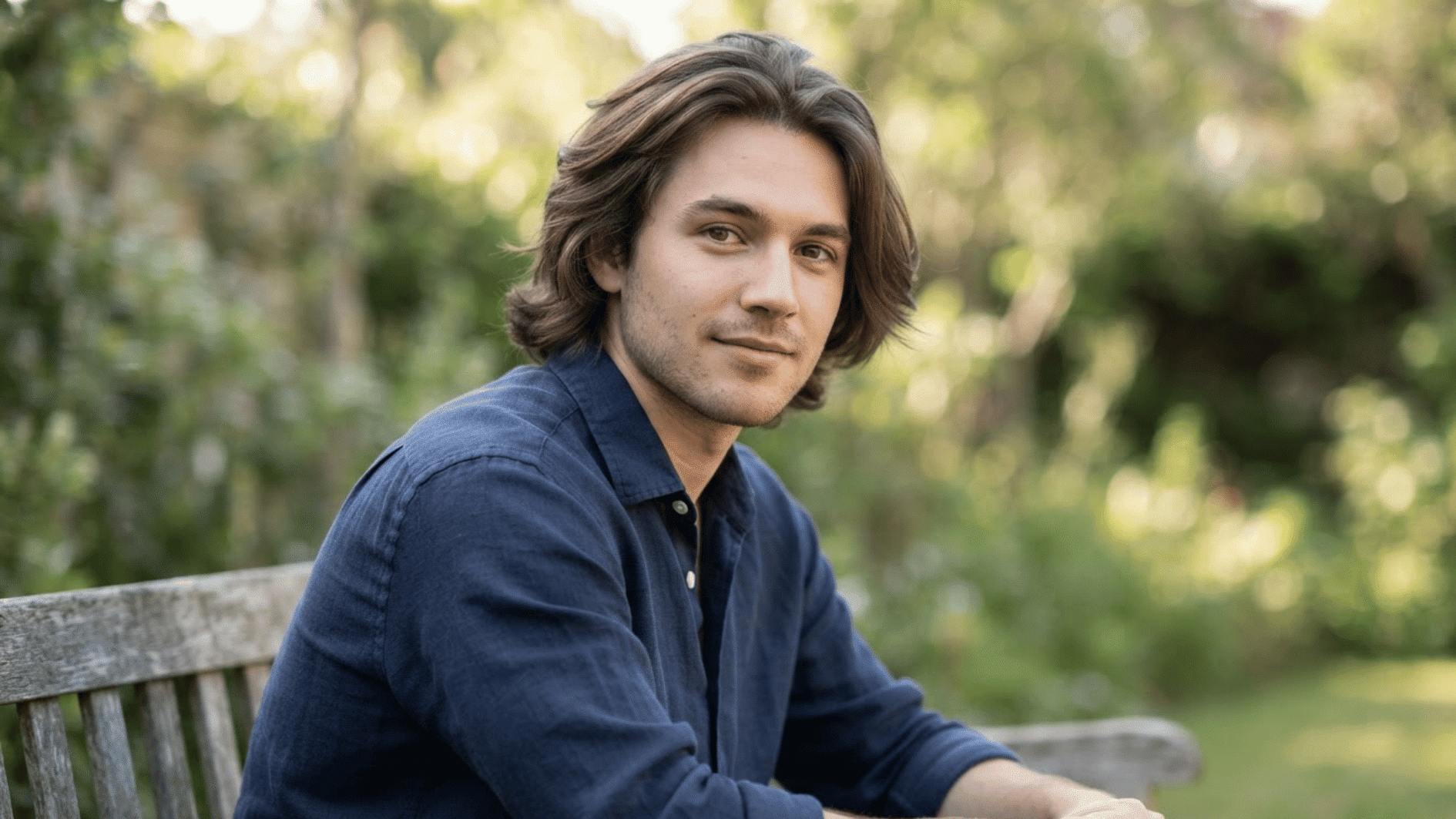 man with long flow haircut sitting outdoors showing layered hair and natural movement