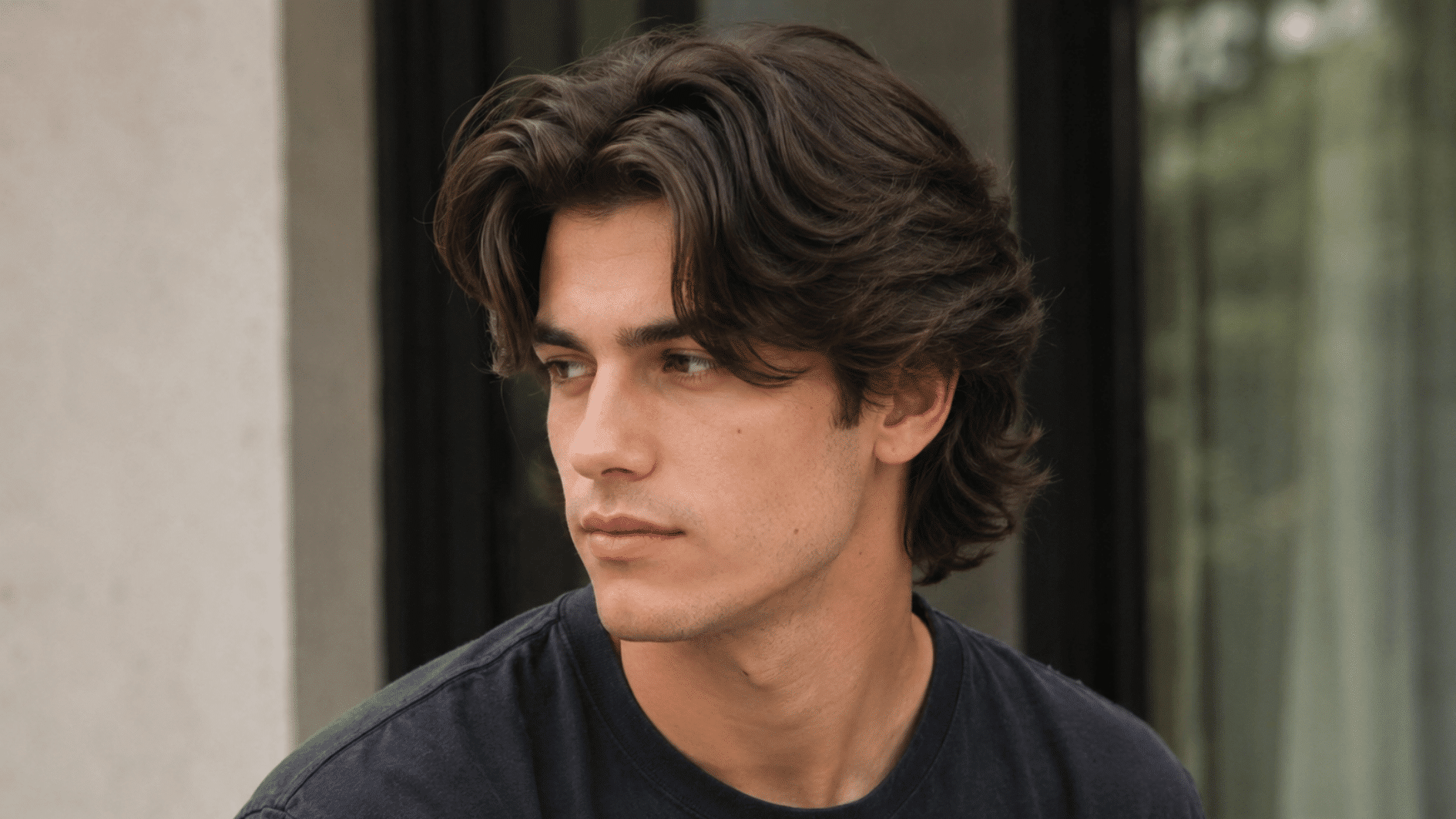 man with medium length flow haircut indoors showing thick layered hair and natural texture