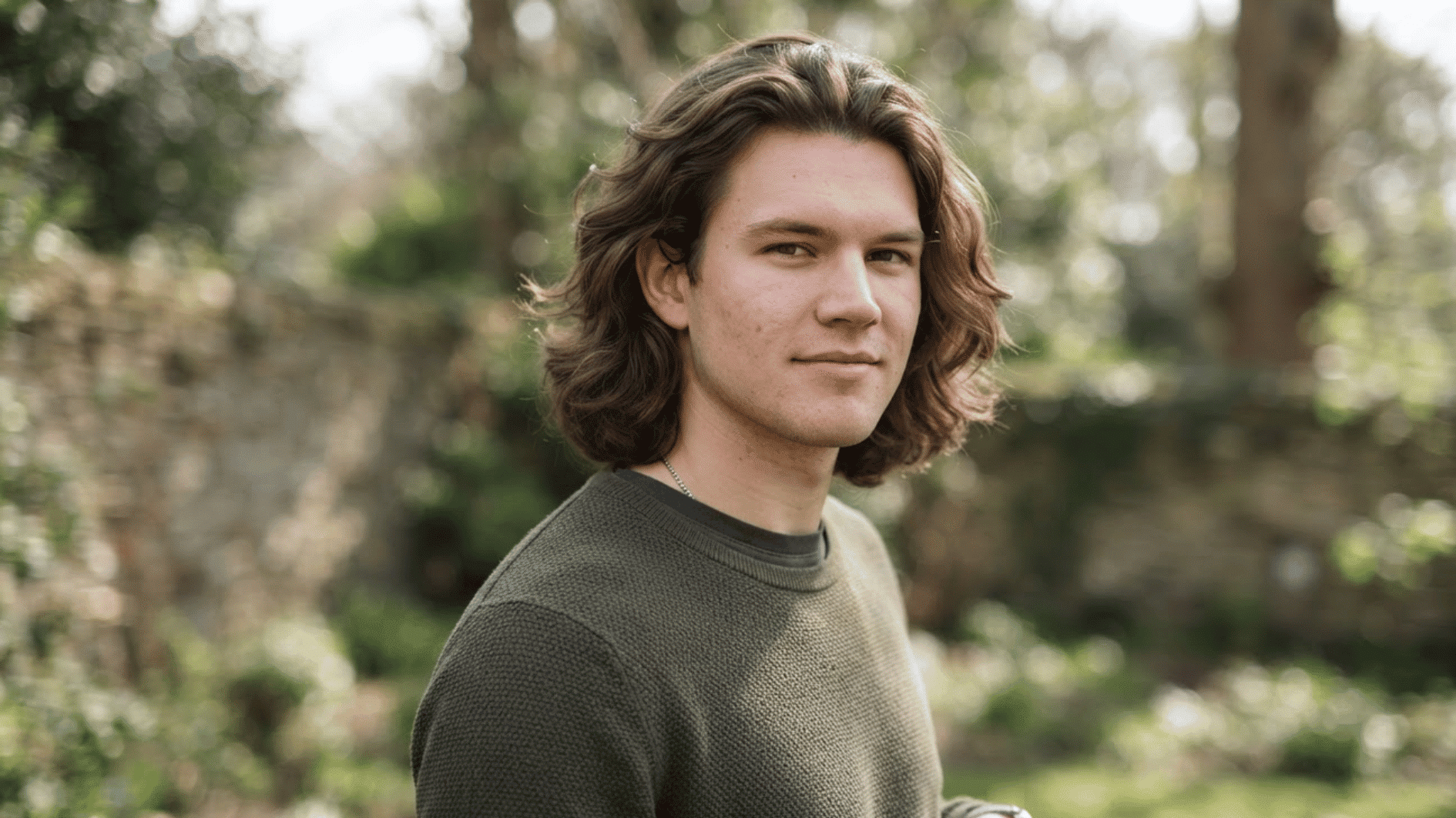 man with medium length flow haircut outdoors showing layered texture and natural wavy hair movement