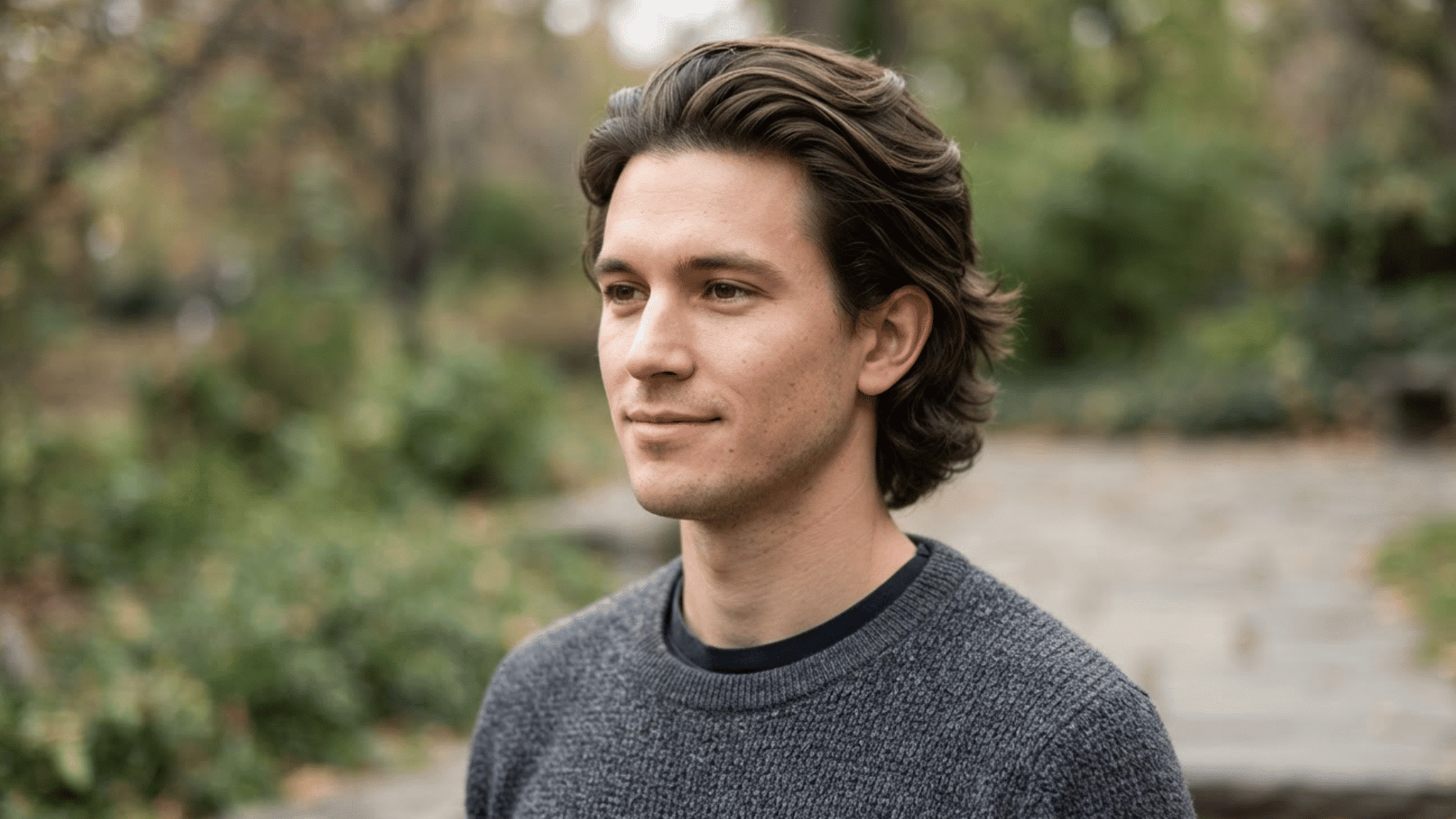 man with medium length flow haircut outdoors showing smooth layered hair and swept back texture