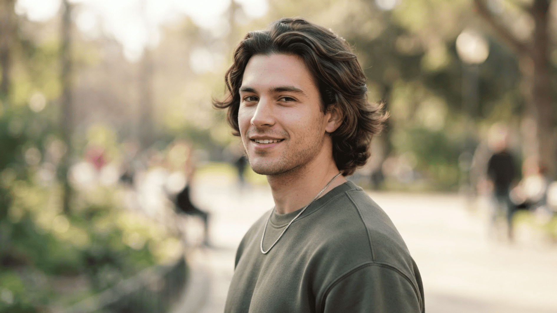 man with medium length flow haircut outdoors showing textured layers and natural swept back hair style