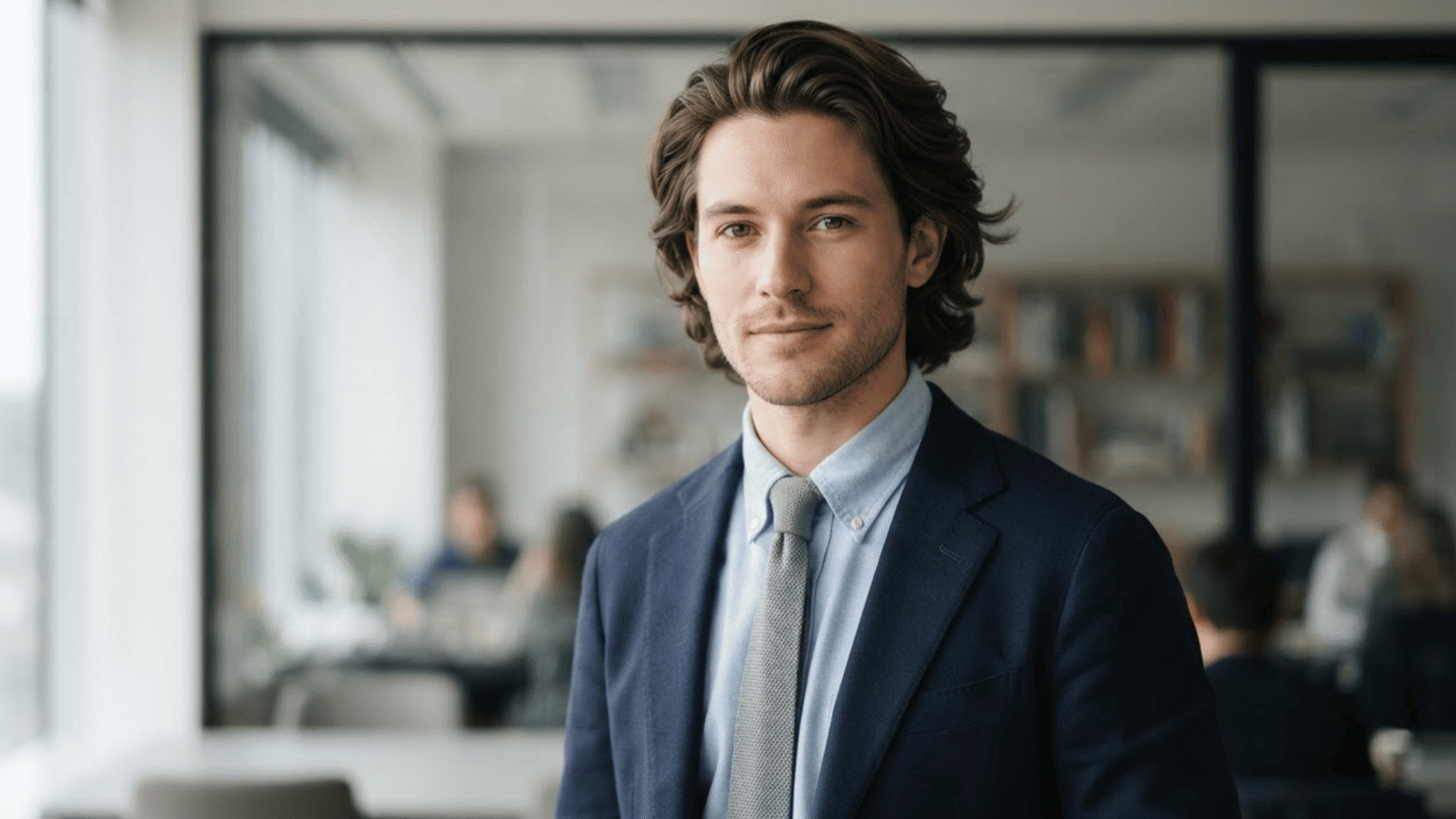 man with medium length flow haircut wearing suit with textured swept back hair style indoors