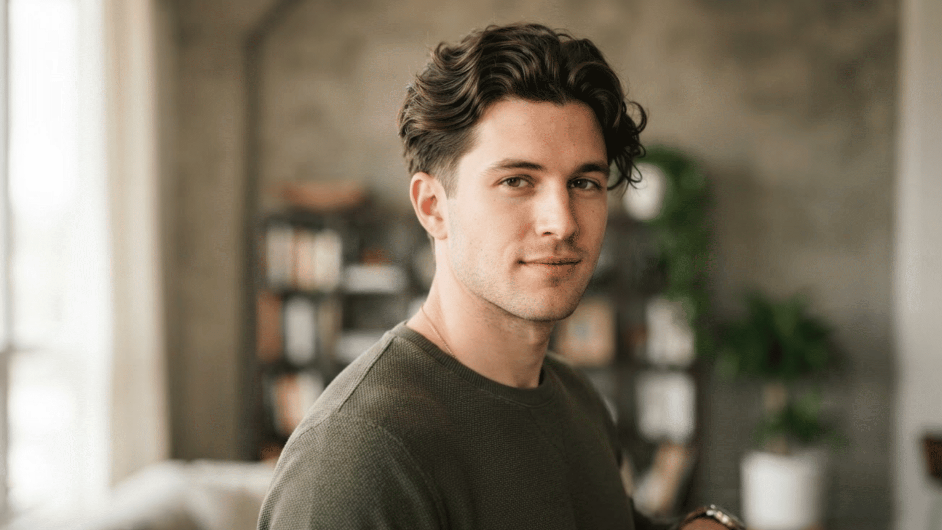 man with short textured flow haircut indoors showing natural volume and swept back hair style