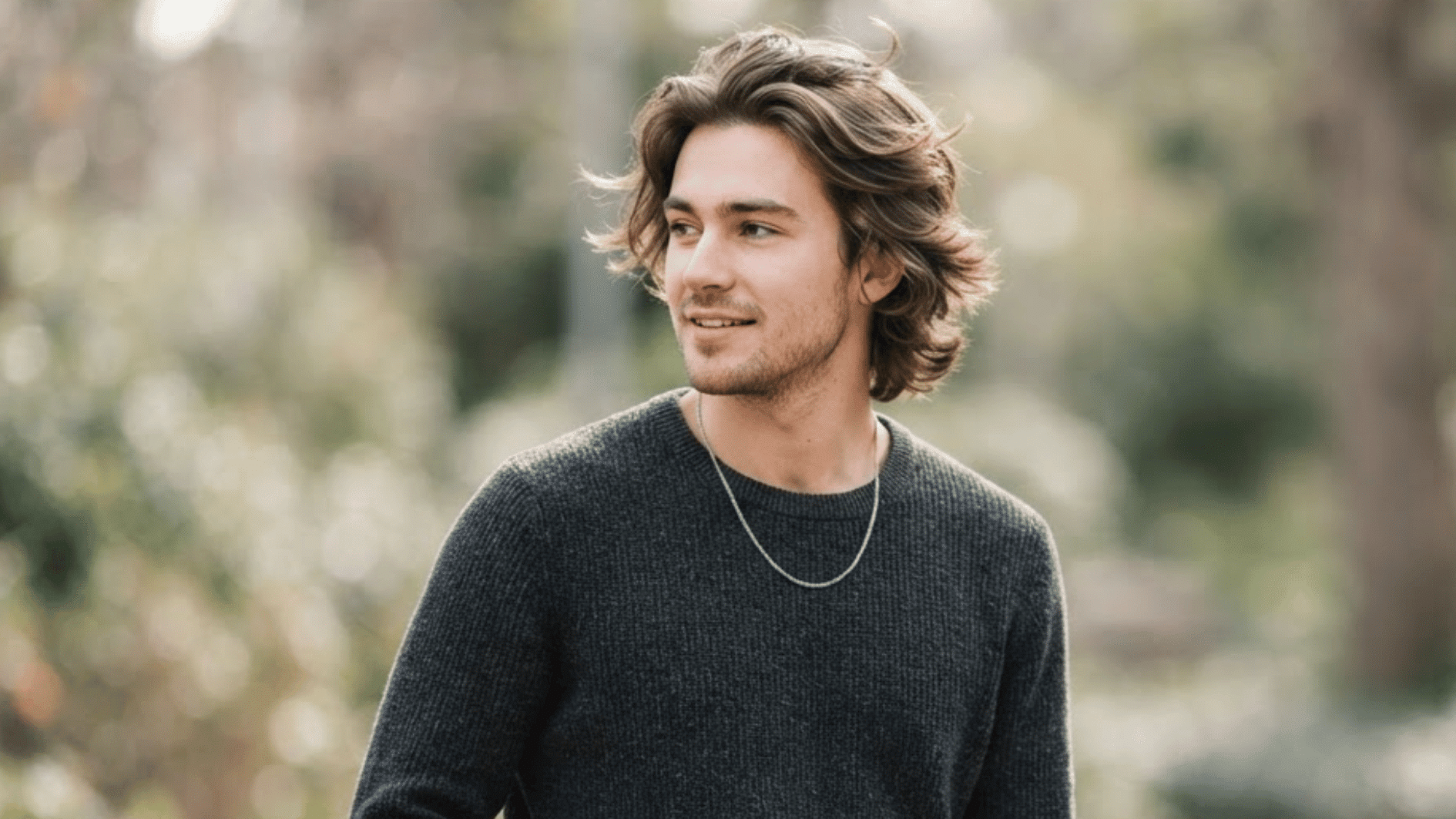 man with wavy flow haircut outdoors showing layered texture and natural swept back hair style