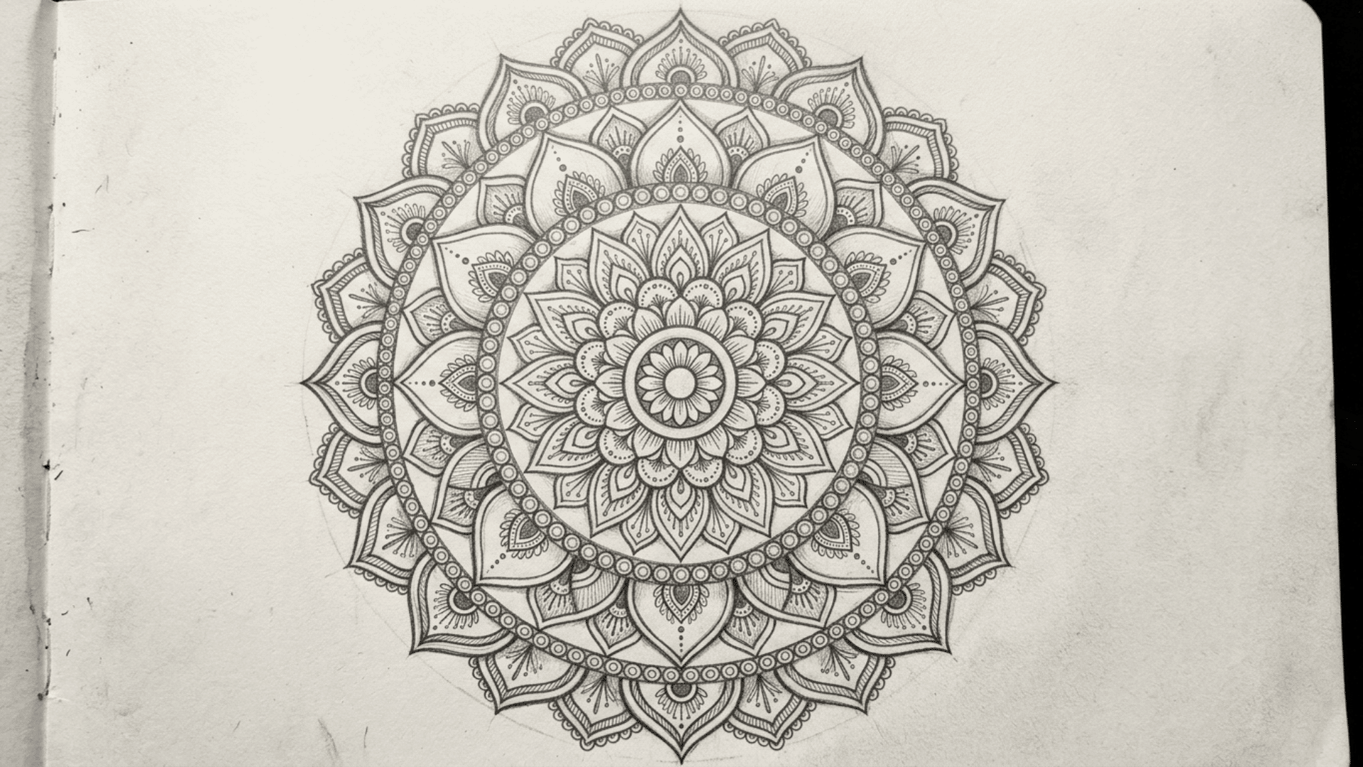 symmetrical pencil sketch of a mandala pattern built from repeating circles and petals