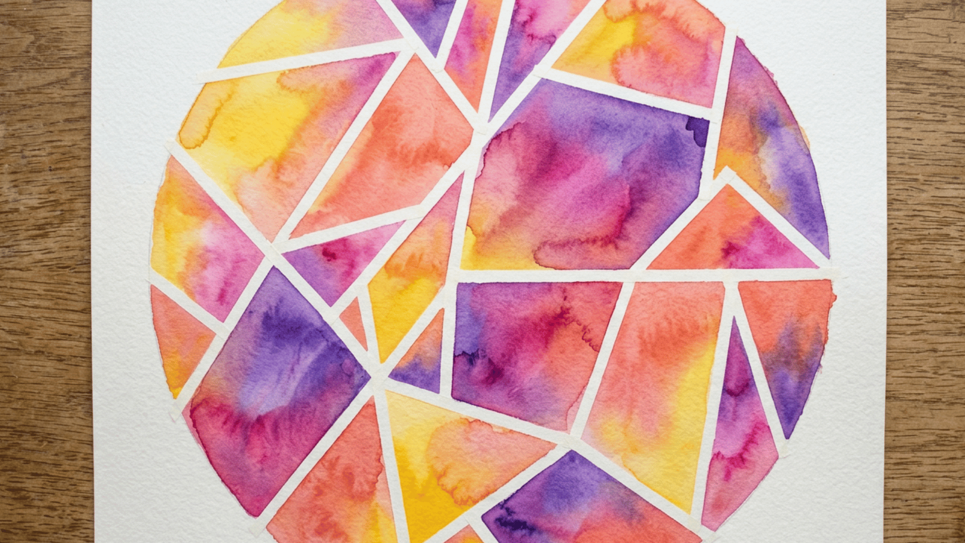 vibrant circular watercolor painting with stained-glass style geometric triangular sections in bright pink, purple, orange and yellow tones on white paper
