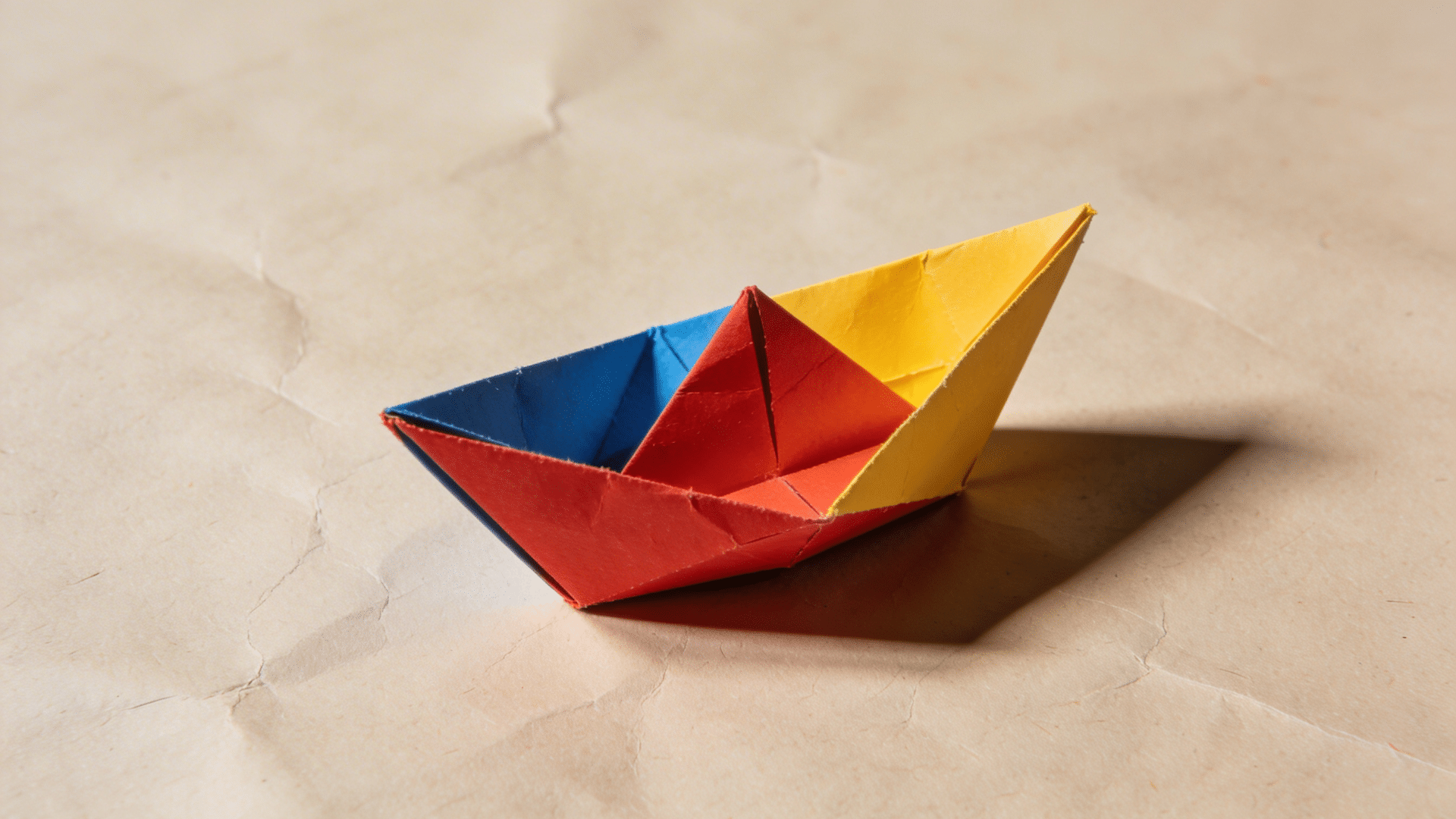 origami paper ship created with multi color sheets and carefully folded on a table.