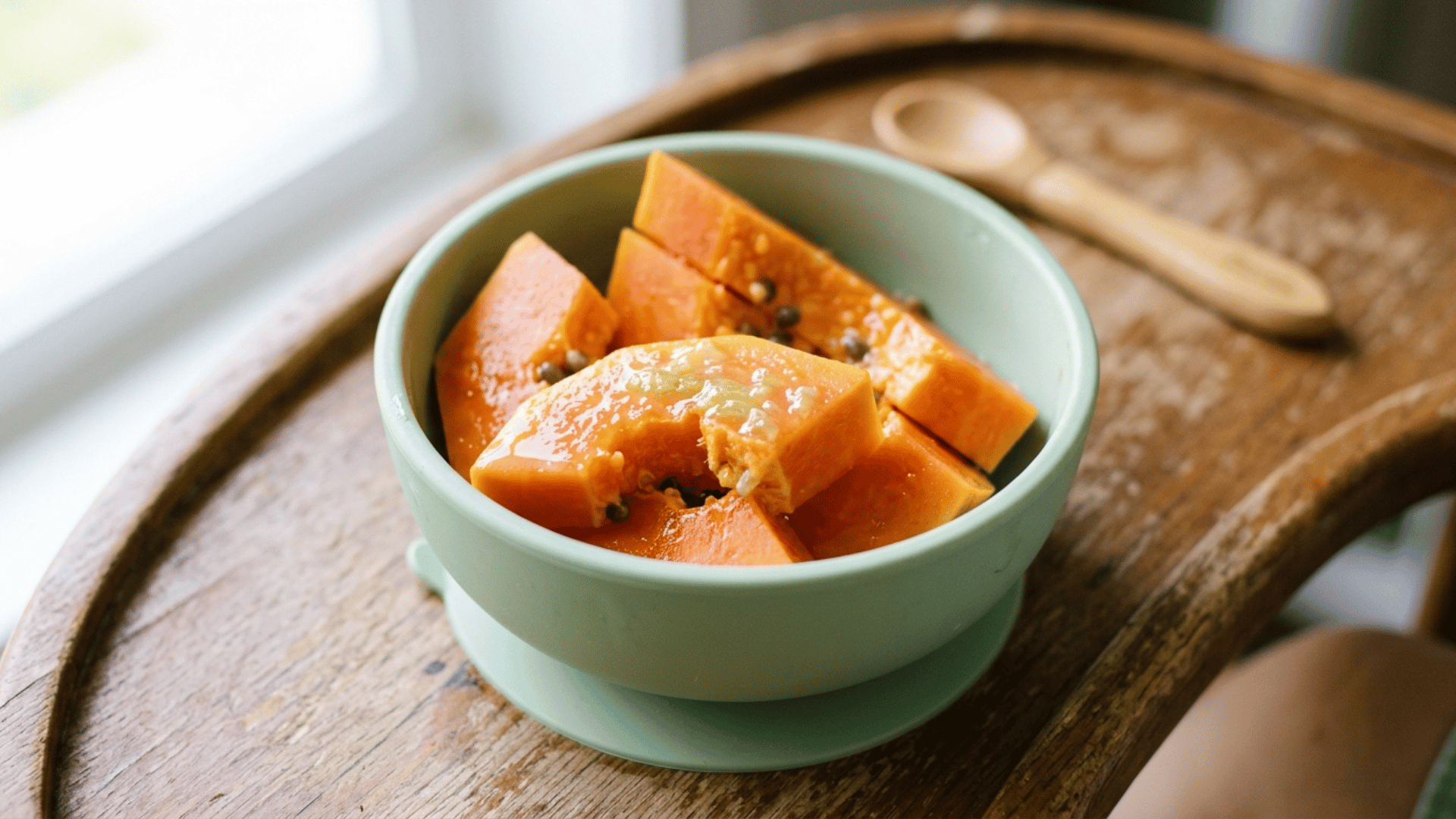 papaya wedges with lime juice served in a green suction bowl for baby