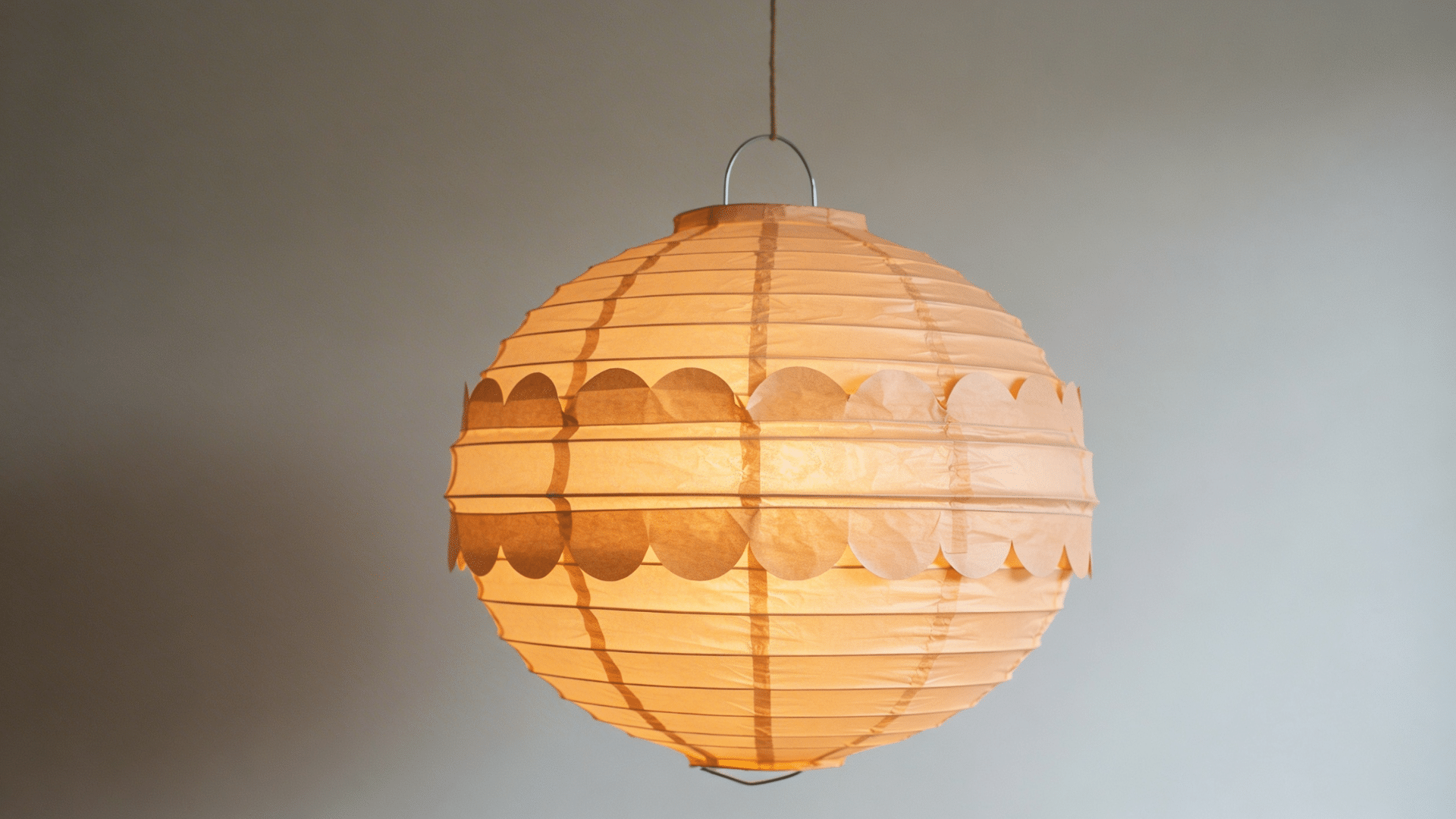 paper lantern with cut slits and a curved shape hanging with a small handle on top