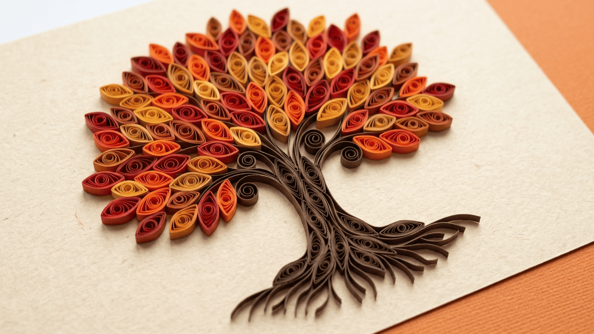 stunning quilled paper art depicting an autumn tree with vibrant red, orange and yellow rolled paper leaves on a detailed brown trunk and roots