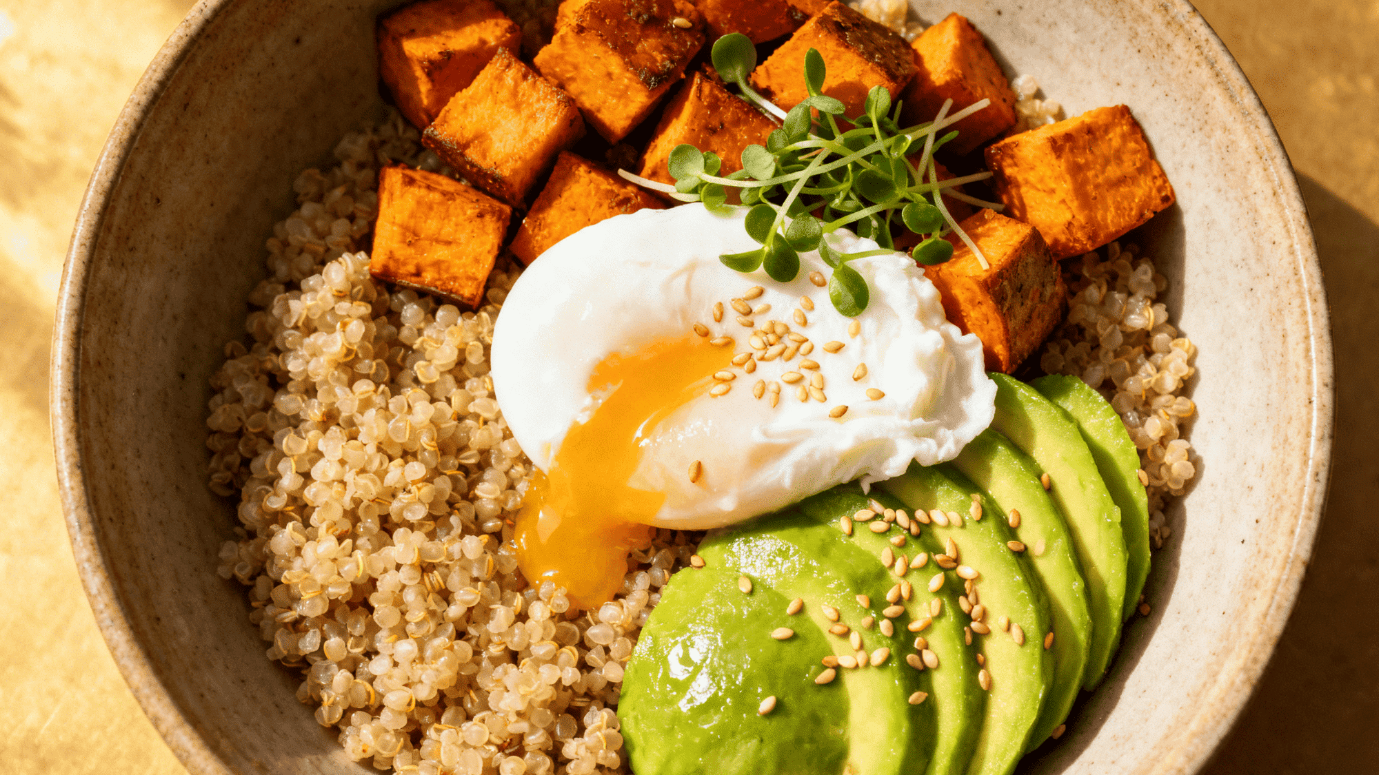 quinoa breakfast bowl with roasted sweet potato, avocado slices, poached egg, microgreens, sesame seeds (1)