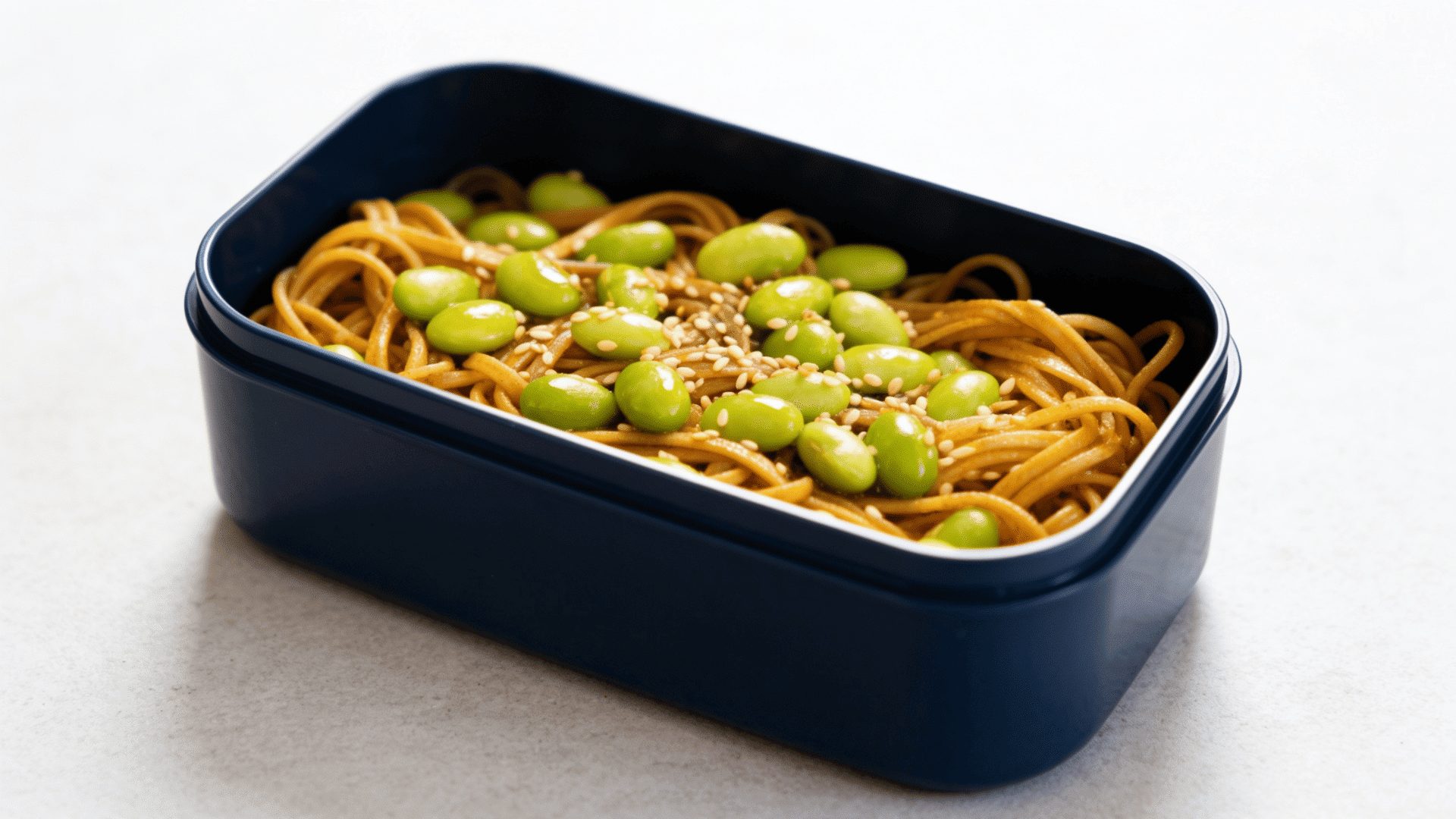 soba noodles and edamame in a deep navy-blue stainless steel bento box