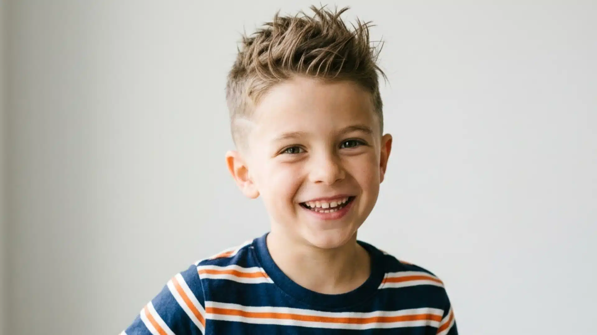 Short spiky hairstyle on a young boy with spiked volume and closely faded sides