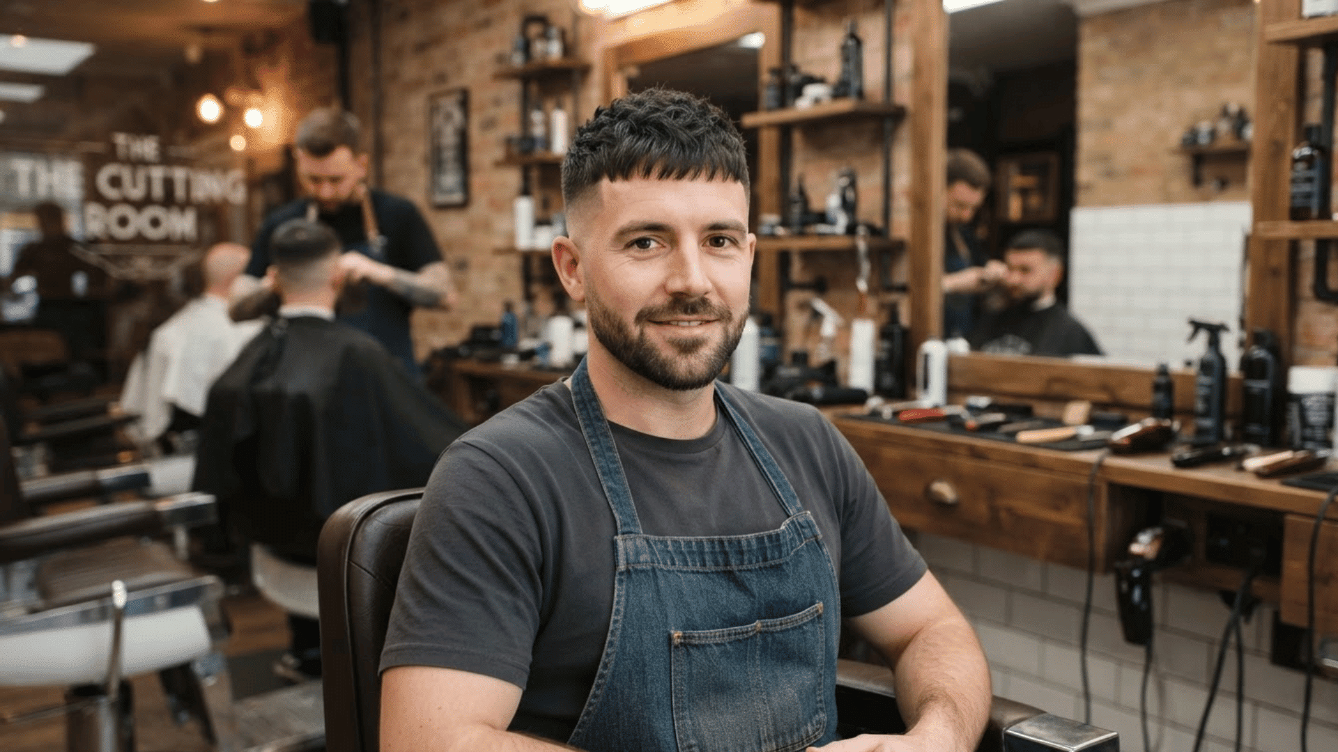 short textured low fade haircut with cropped fringe and clean sides on man sitting in barber shop chair