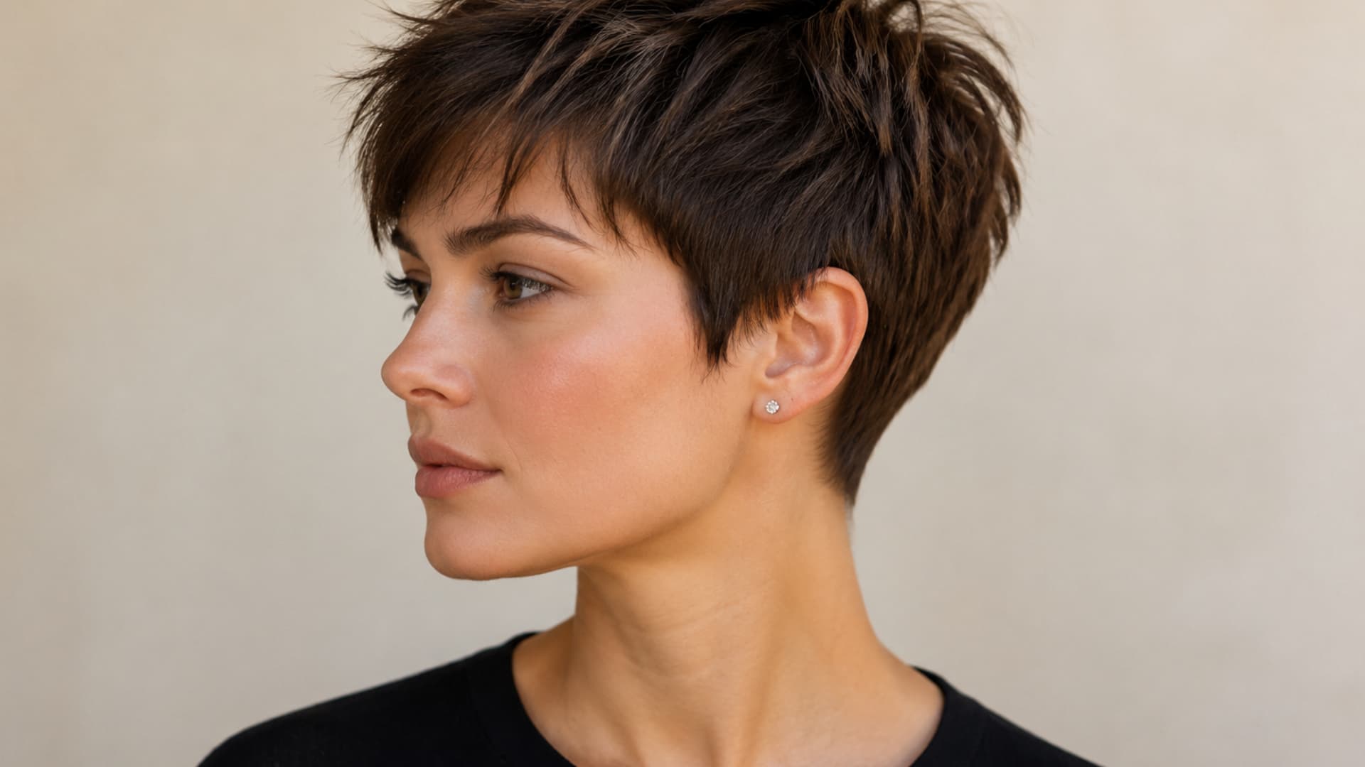 short textured pixie haircut on thick hair with layered volume and soft natural styling in a clean studio setting