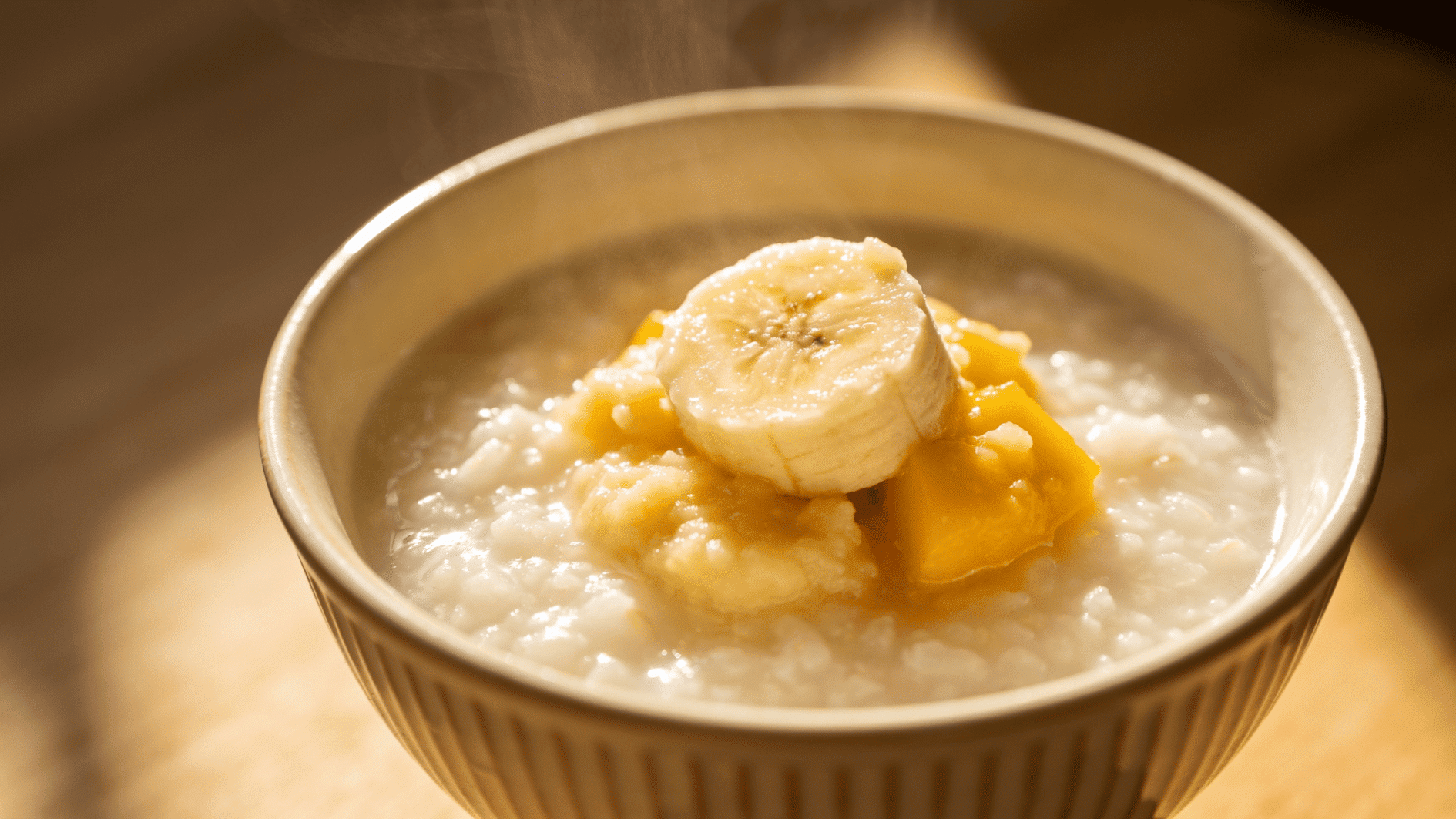 small bowl of soft creamy coconut rice porridge topped with mashed fruit