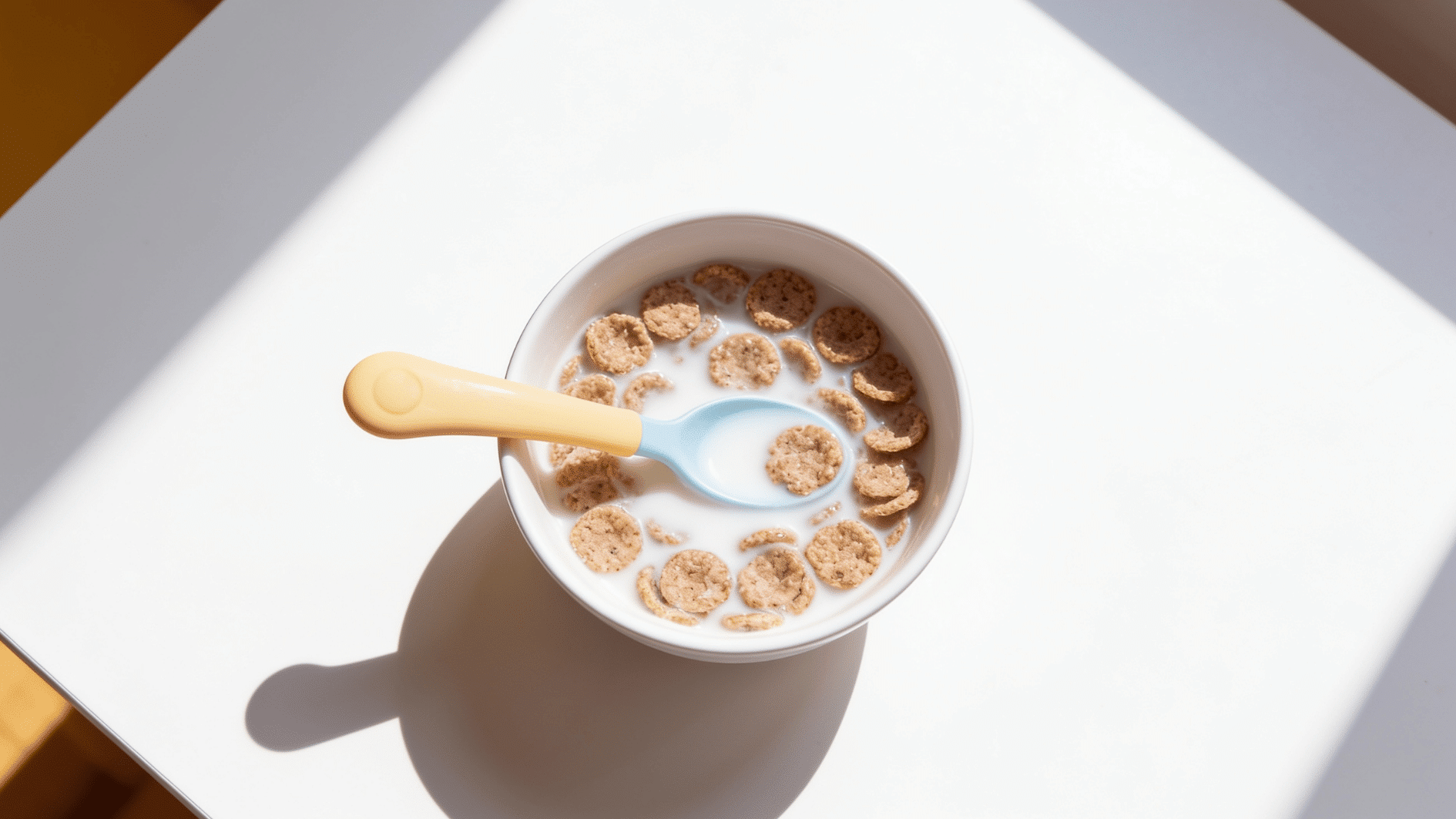 small bowl of whole-grain low-sugar cereal softening in milk with a toddler spoon,
