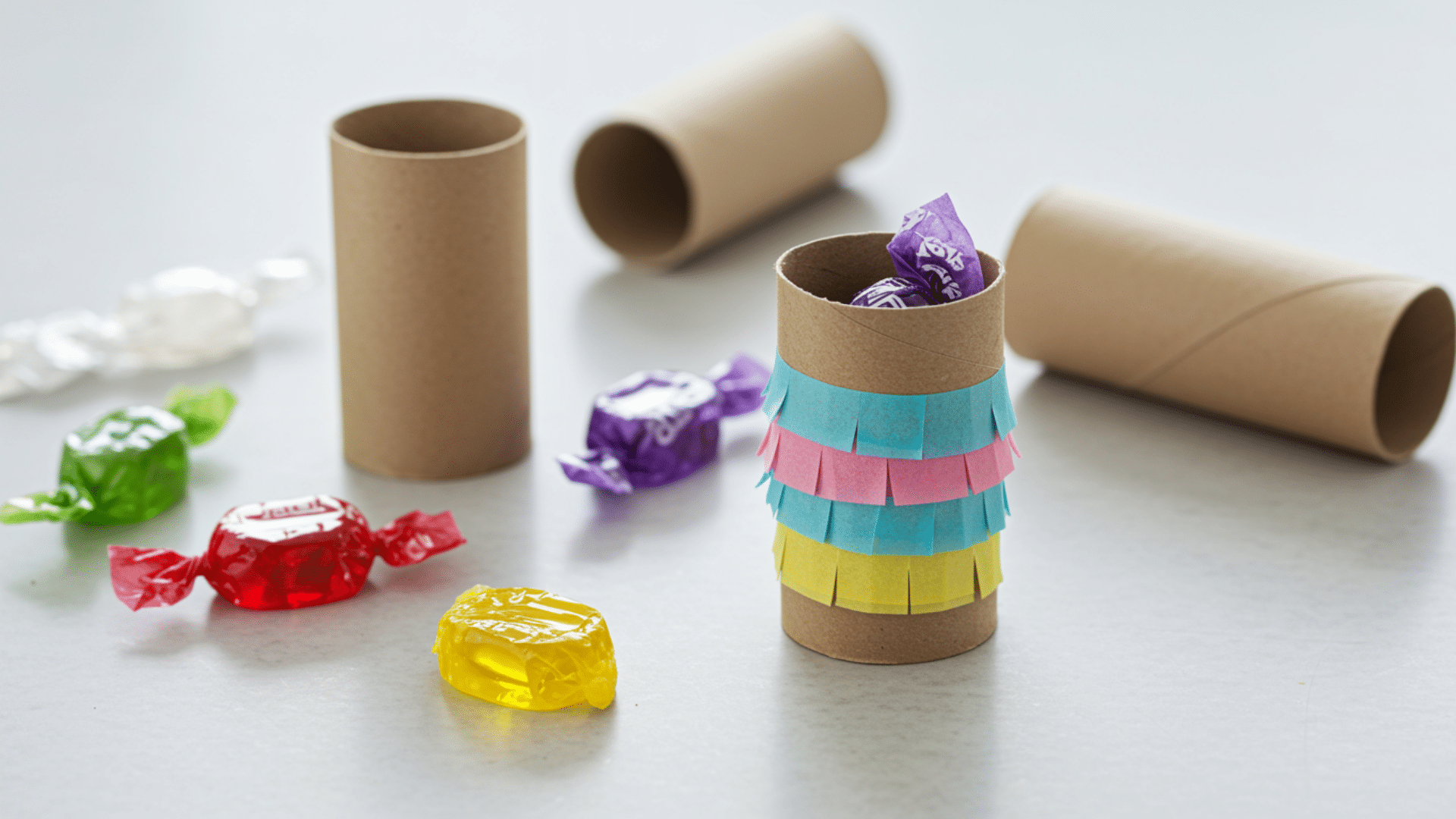 small paper roll piñatas covered in fringed tissue paper with sealed ends.