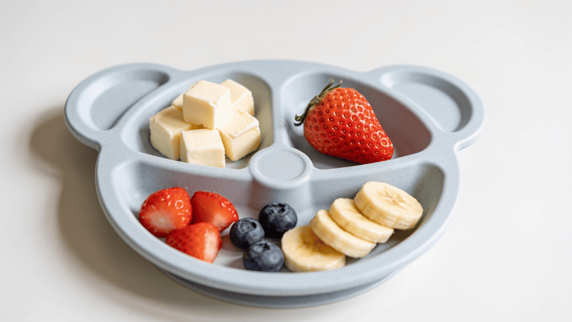 _small toddler plate with soft cheese cubes and bite-sized soft fruit arranged